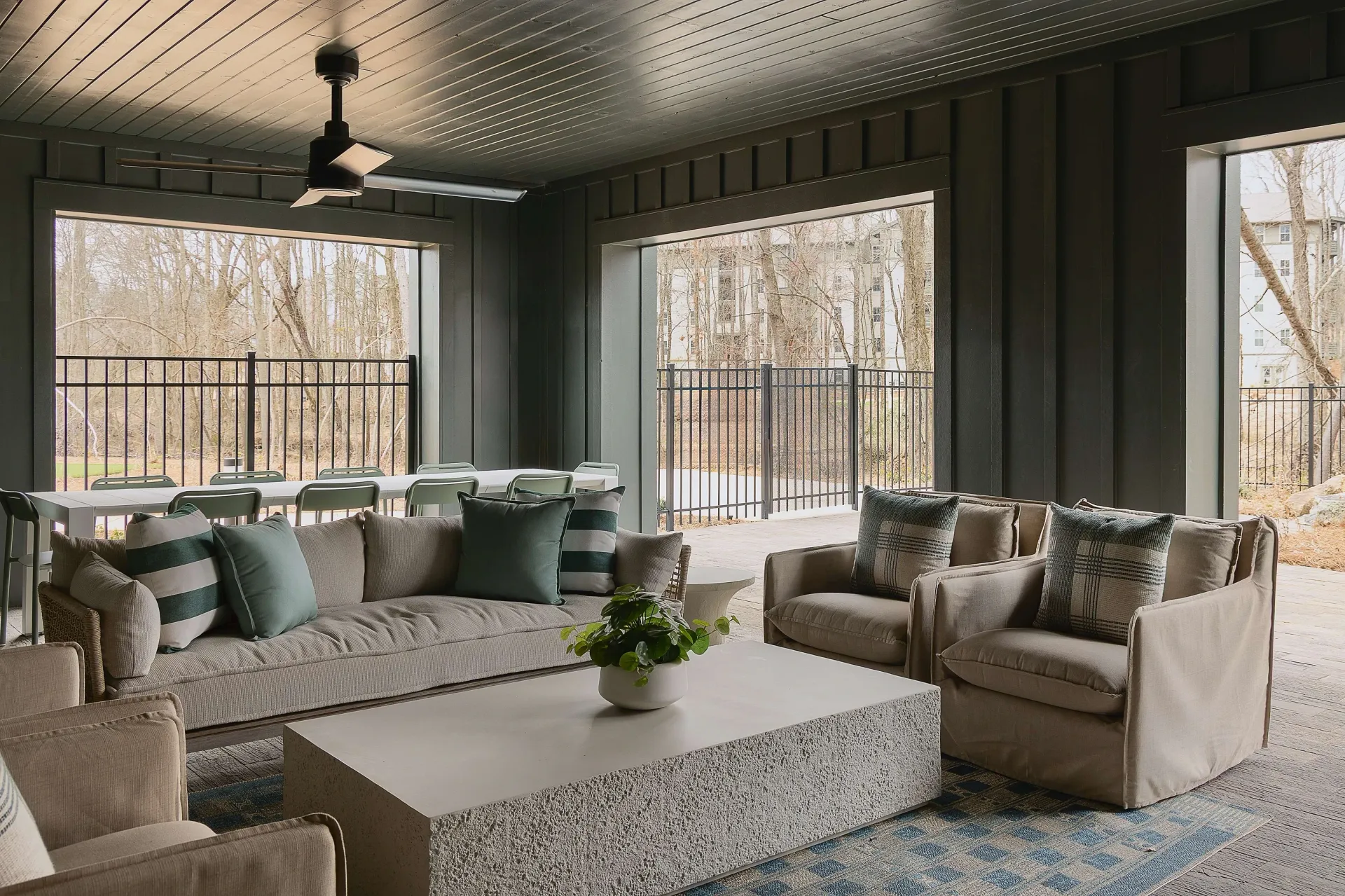 Indoor common area with comfortable seating and a large table overlooking an outdoor space with trees and buildings.