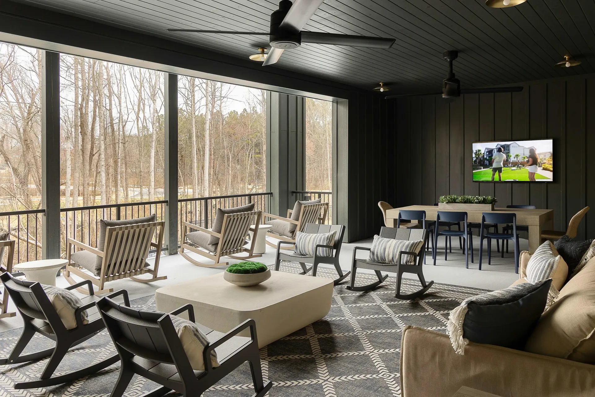 Modern communal lounge area with rocking chairs, a large coffee table, and a dining table with chairs.