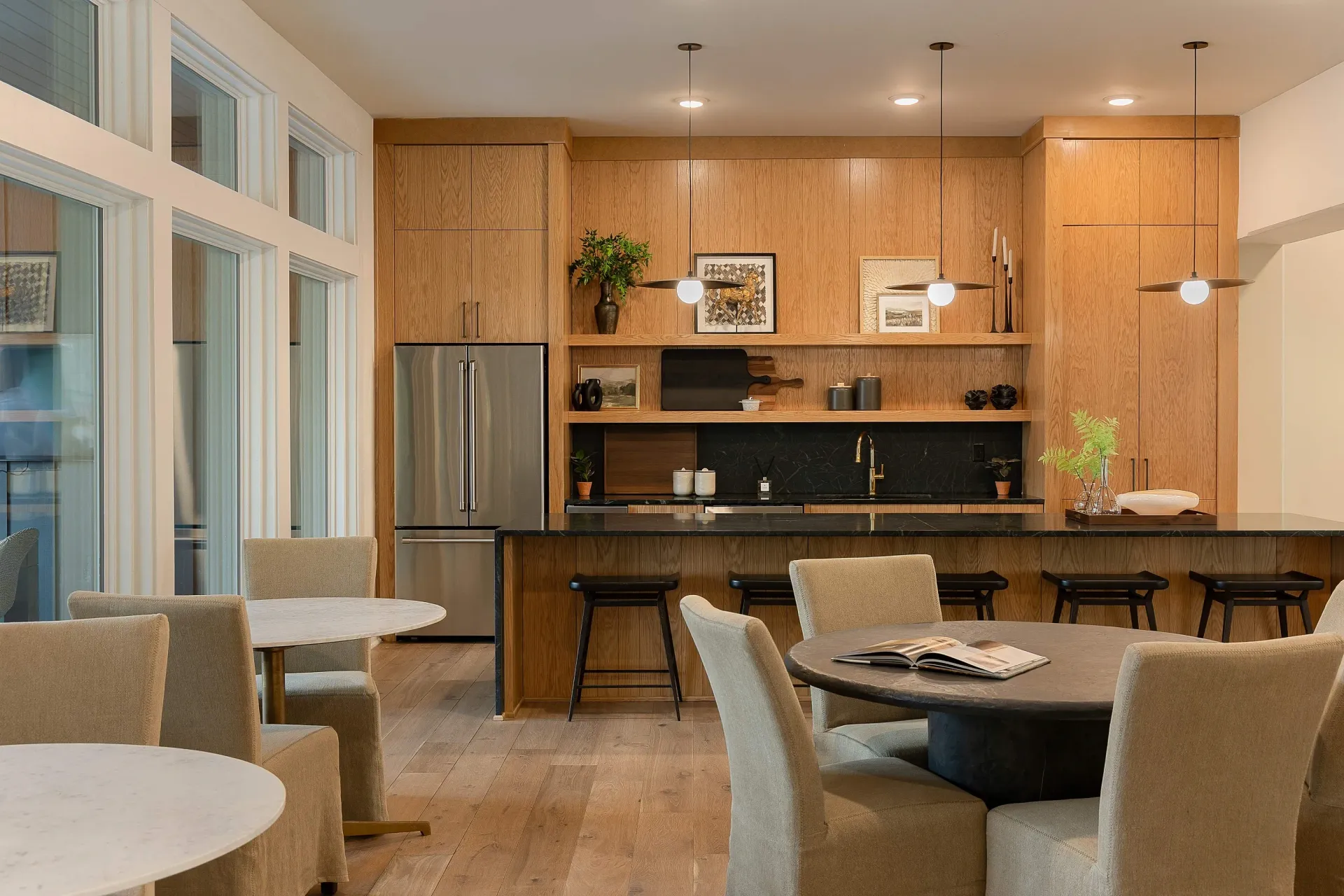 Modern kitchen with wood cabinets, black countertops, and stainless steel appliances.