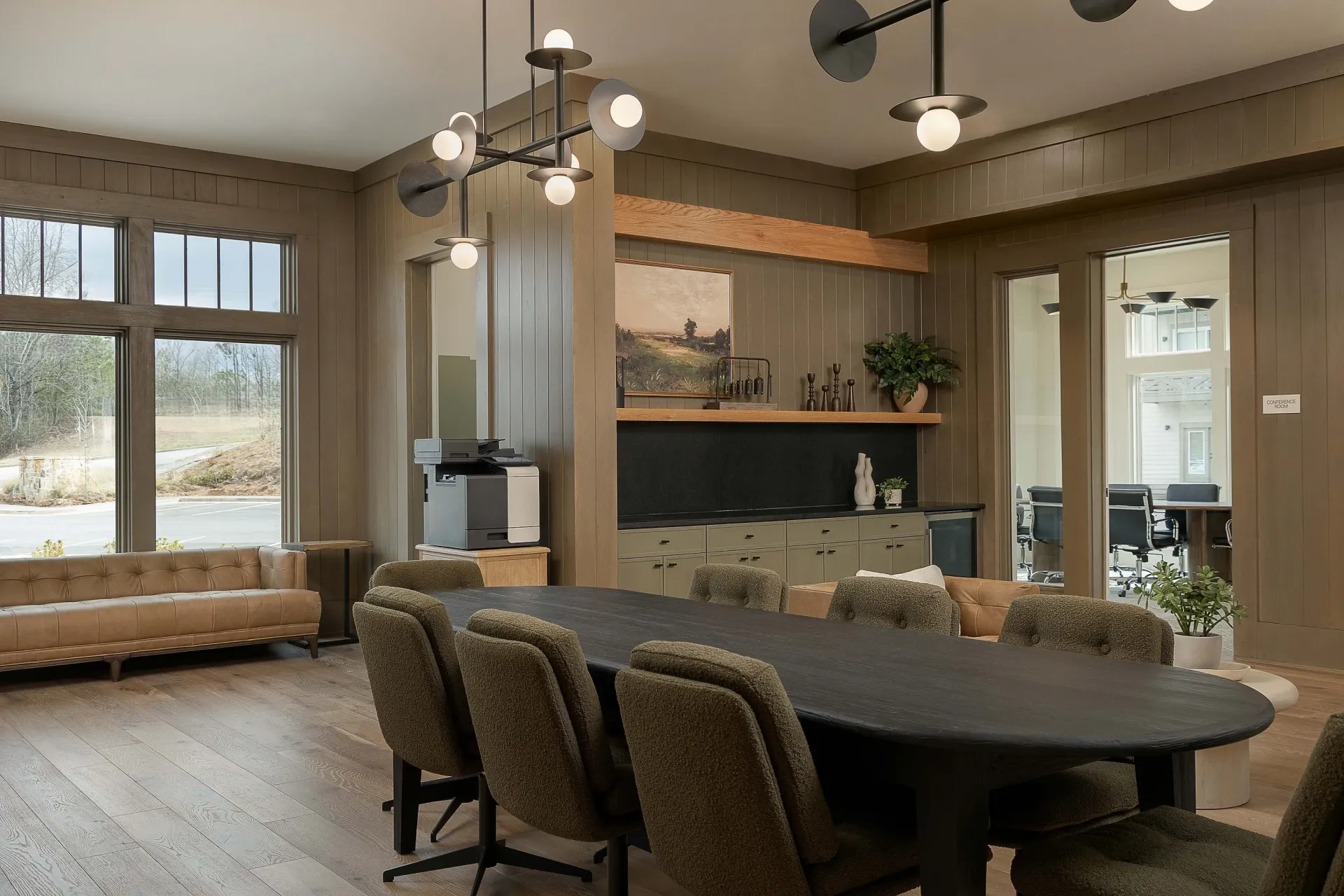 Business center with conference table and chairs, printer, and lounge area.
