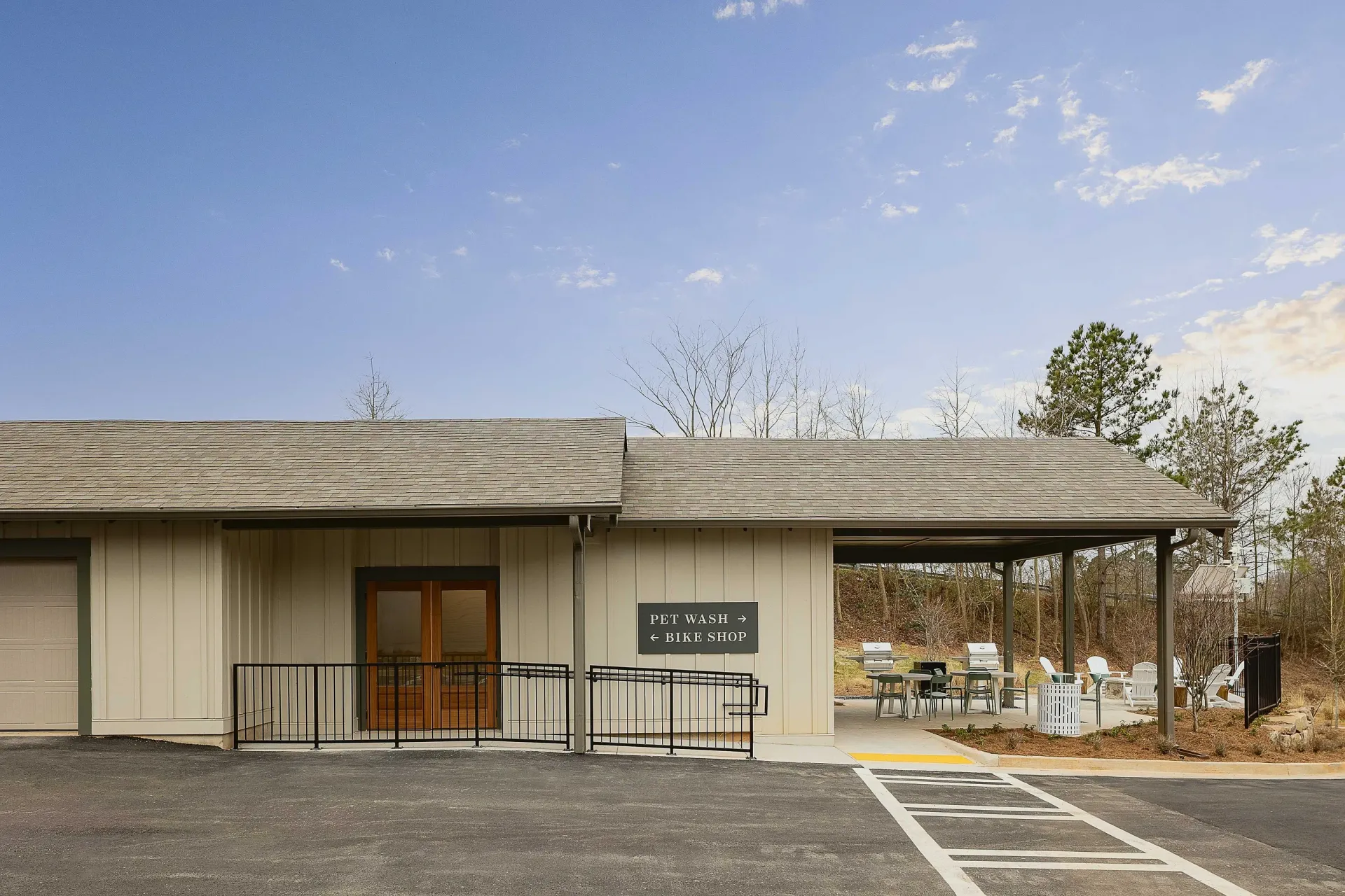 Exterior of the community building with signage for pet wash and bike shop, outdoor seating and grills.