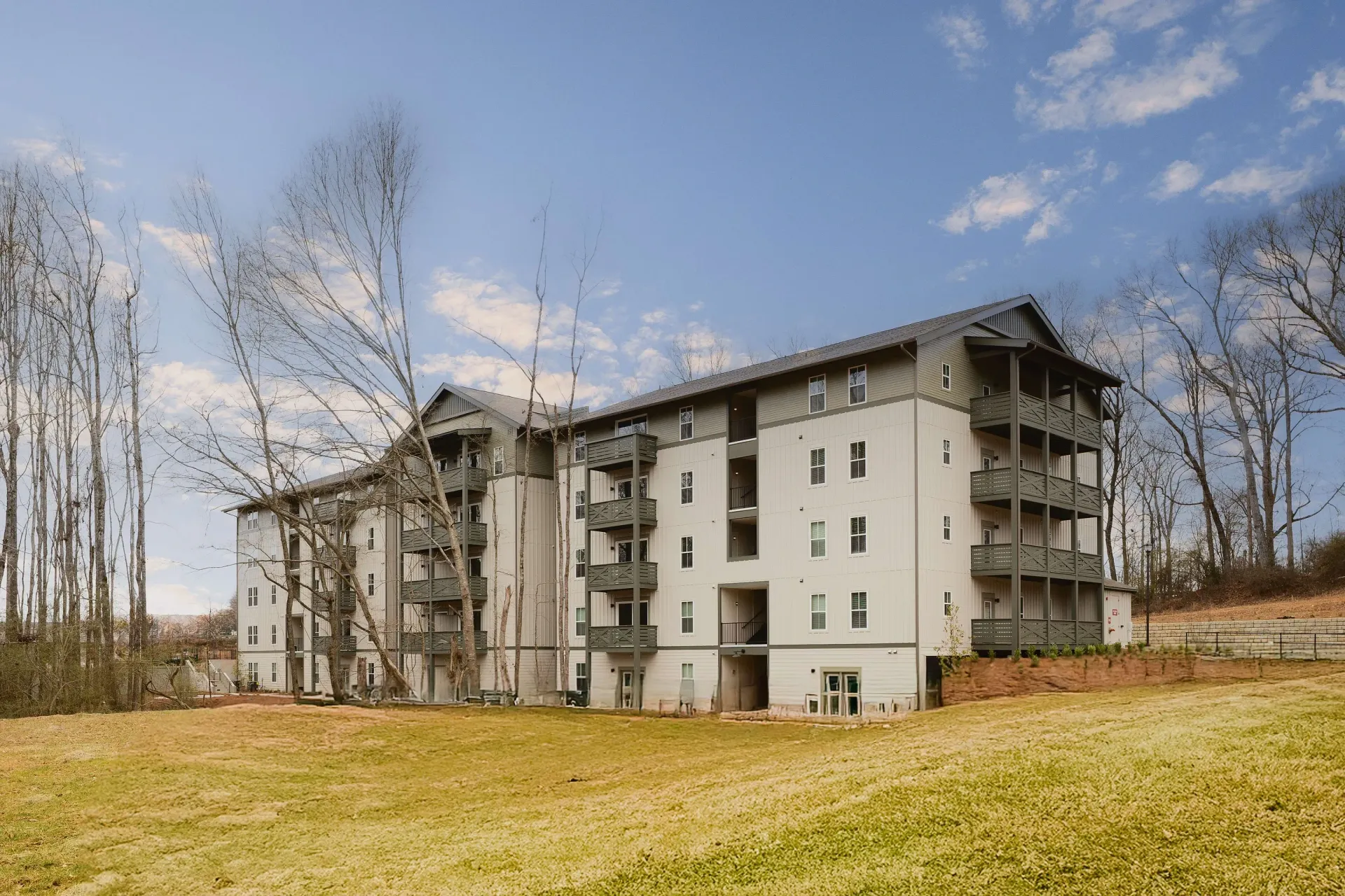 Exterior view of a modern apartment building with balconies and surrounding trees.