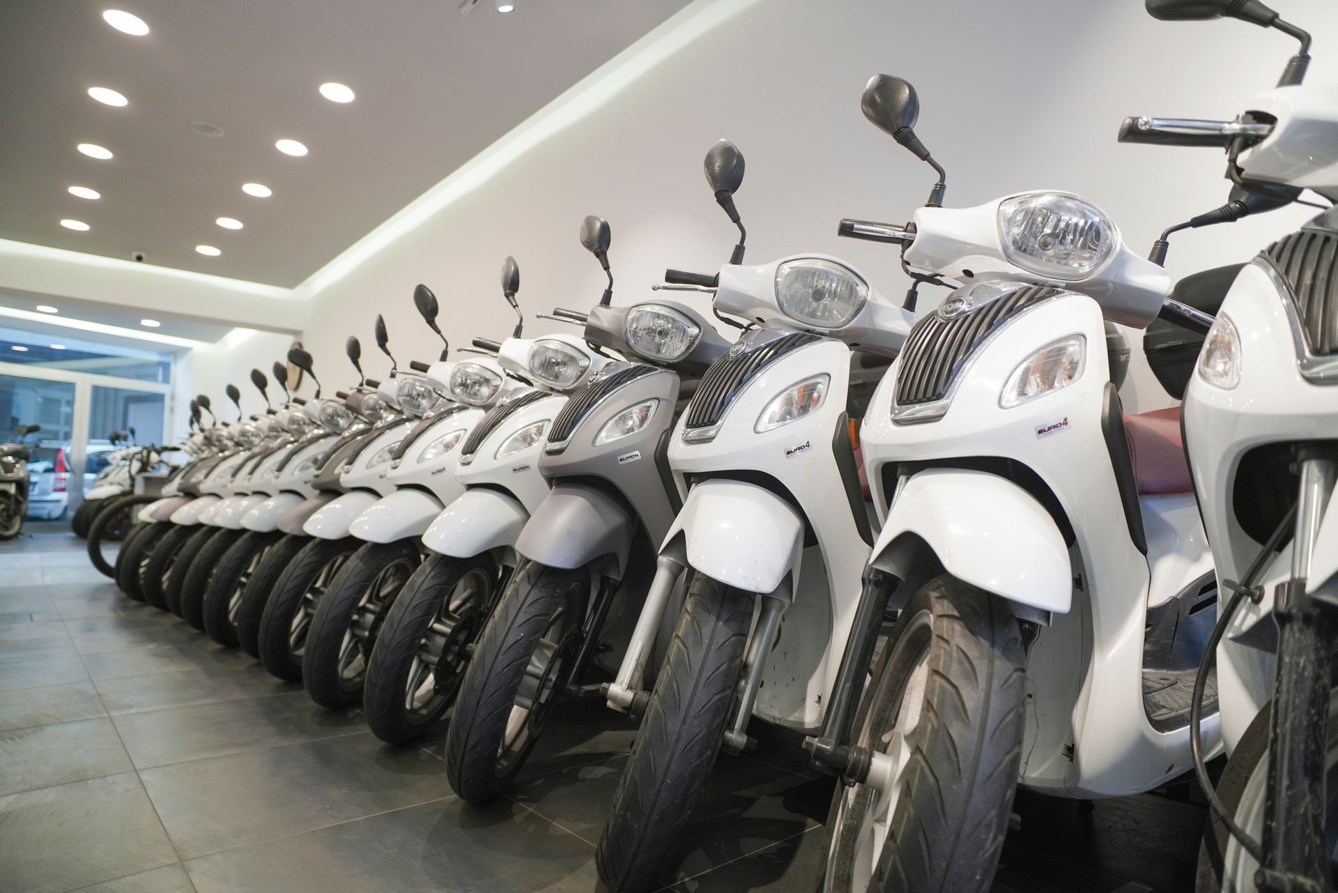 Una fila di scooter bianchi sono allineati in uno showroom.