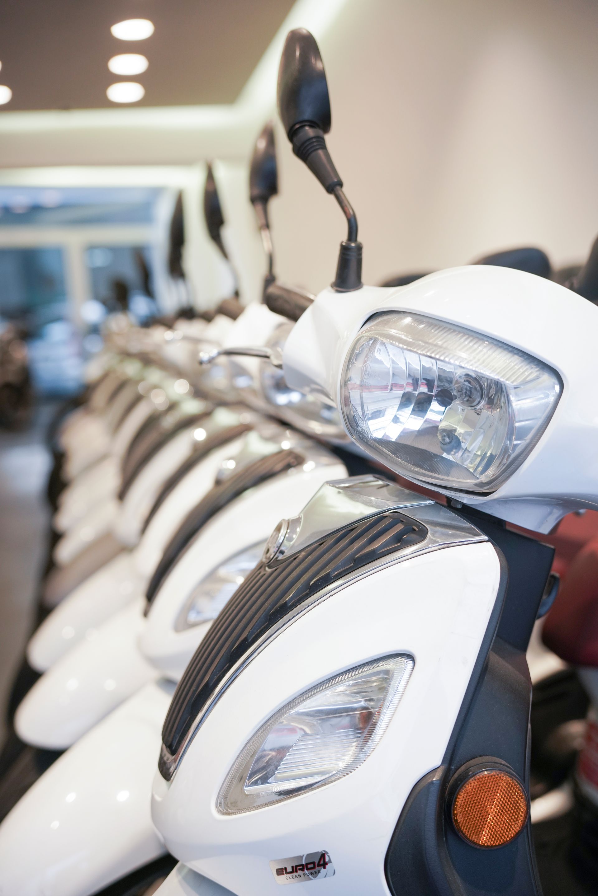 Una fila di scooter bianchi sono allineati in uno showroom.