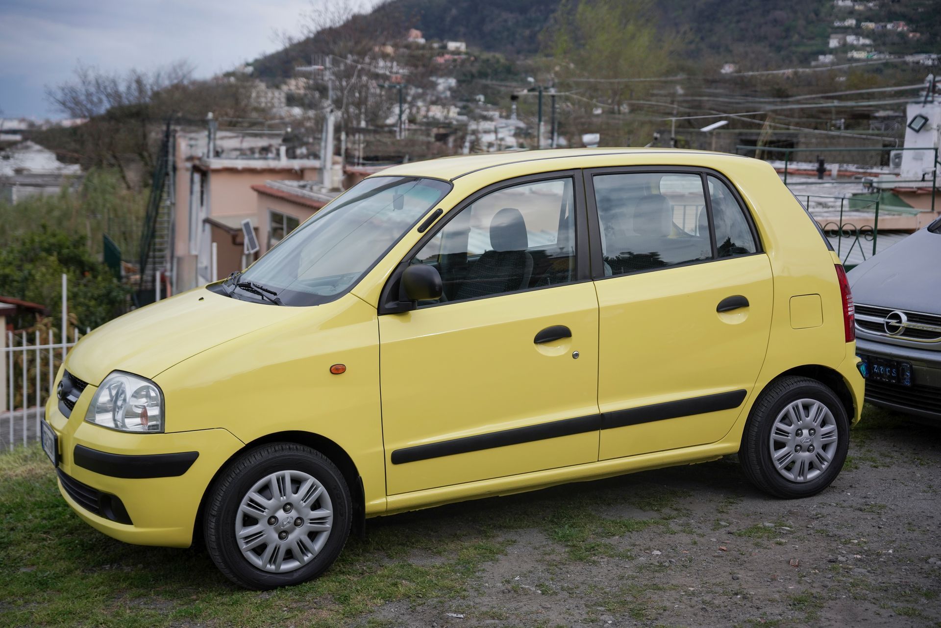 Una piccola macchina gialla è parcheggiata in una zona erbosa