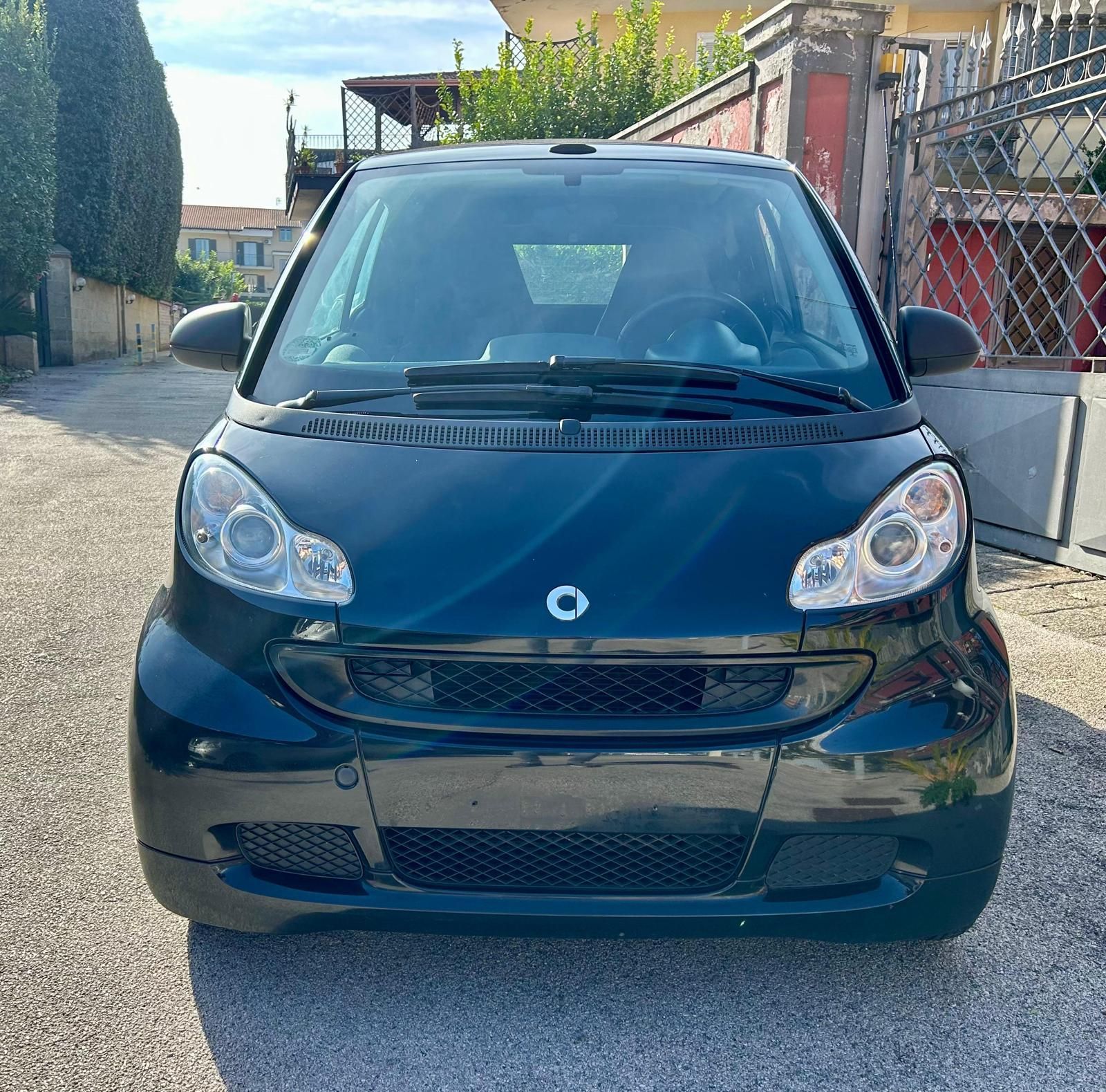 A white smart car with its top down on a white background