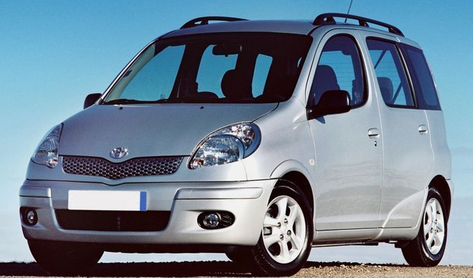 A silver minivan is parked on the side of the road.