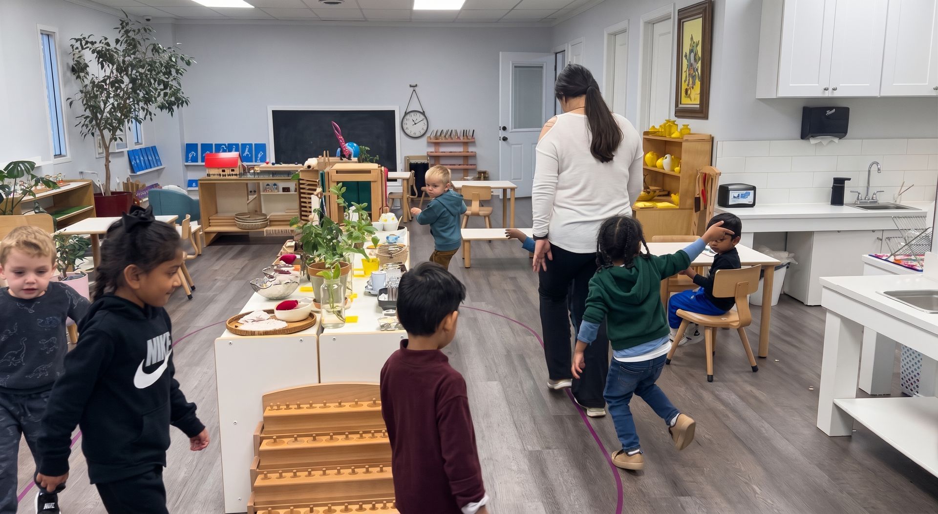 Children in a bright classroom play and gather around tables with toys and art supplies