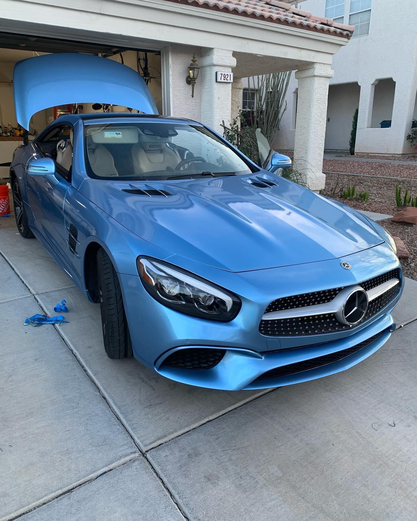 Blue Mercedes coupe parked in a driveway with its hood open in front of a house