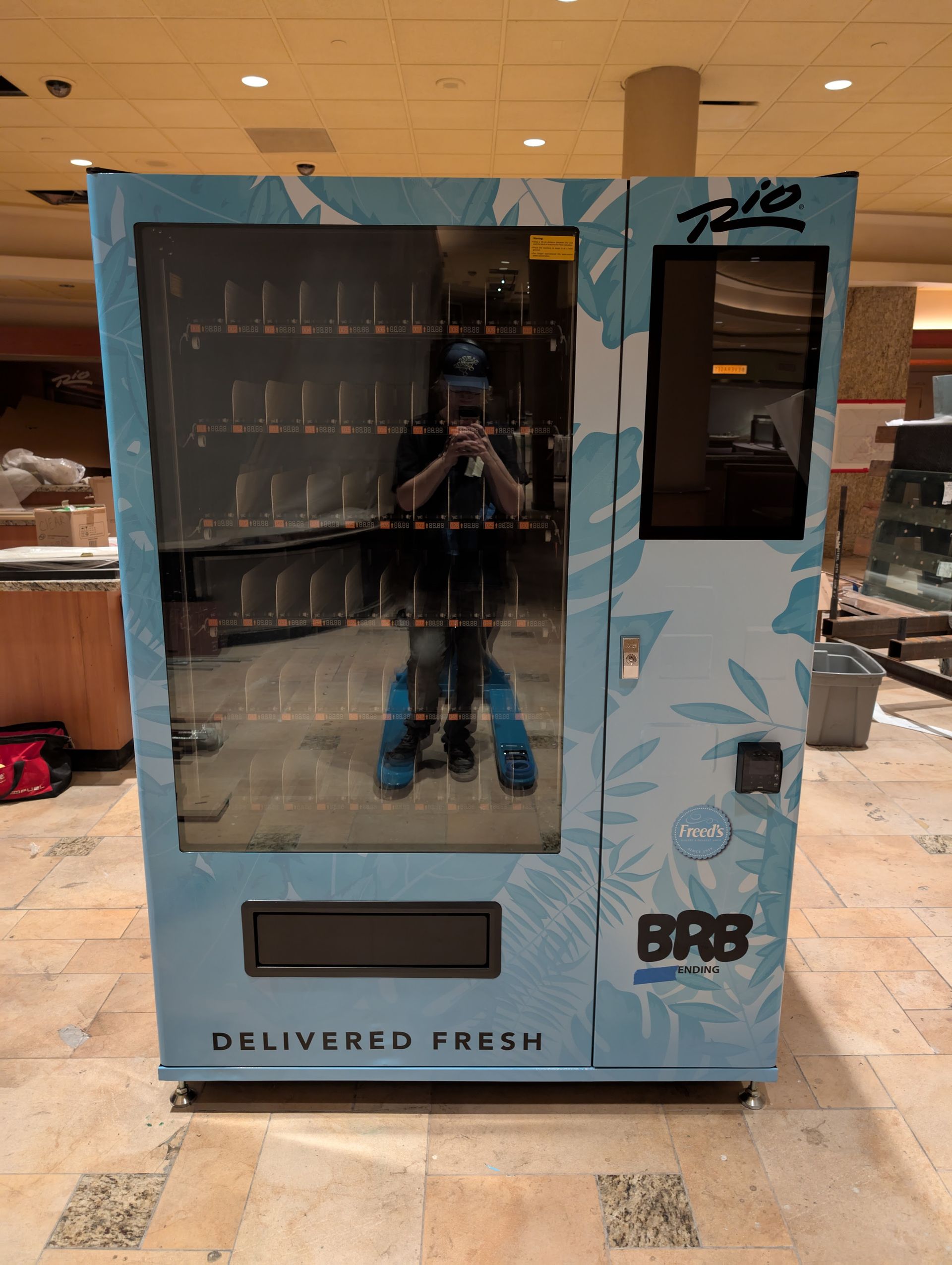 Blue beverage vending machine in a store, with glass front and 