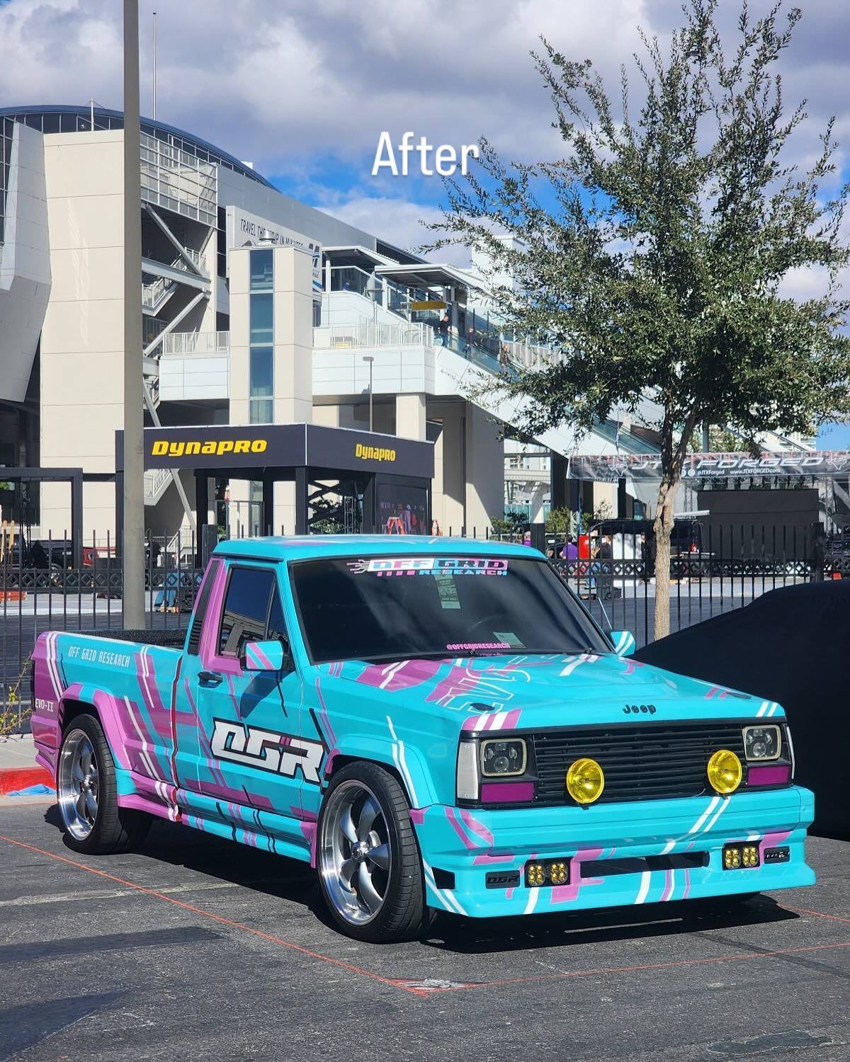 Bright turquoise and pink modified pickup truck parked outdoors in front of a building.