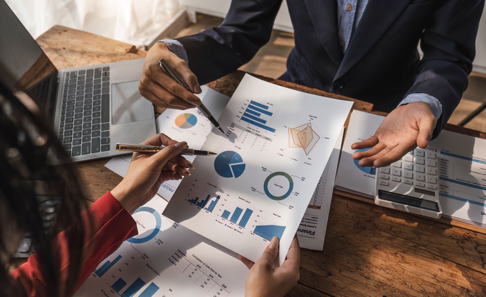 A man and a woman are sitting at a table looking at charts and graphs.