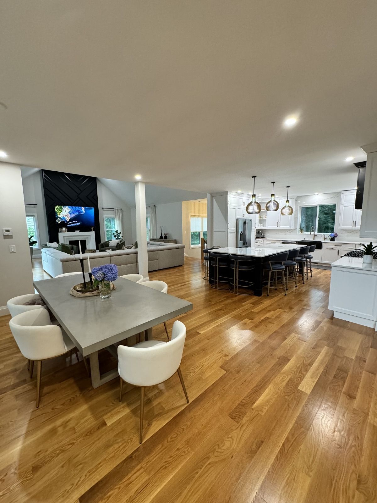 Modern open-concept kitchen and dining area with hardwood floors, white cabinets, and a central island
