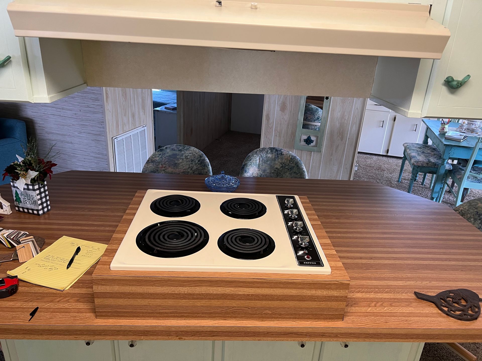 Kitchen counter with a wood-cutout electric cooktop and utensils on a wooden countertop.