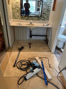 Unfinished vanity area with mirror and tools on the floor during installation or repair.