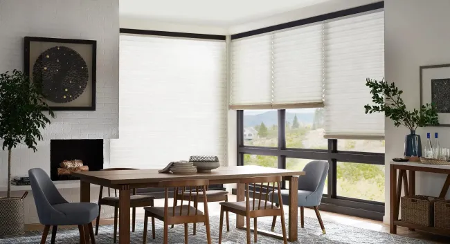 Modern dining room with a wooden table, chairs, large windows, fireplace, and potted plants.