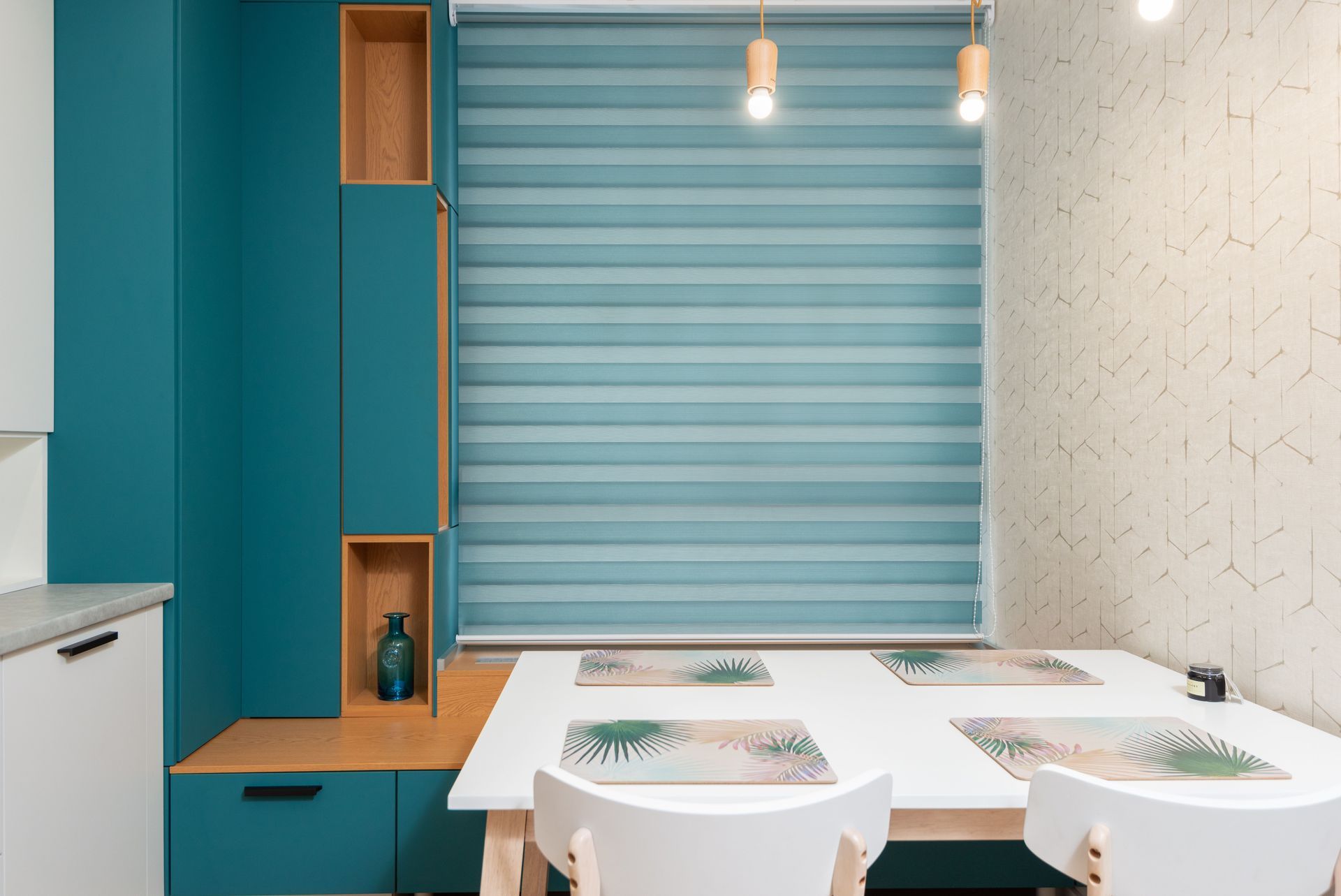 Modern dining nook with teal wall, striped blue blind, white table, and two white chairs