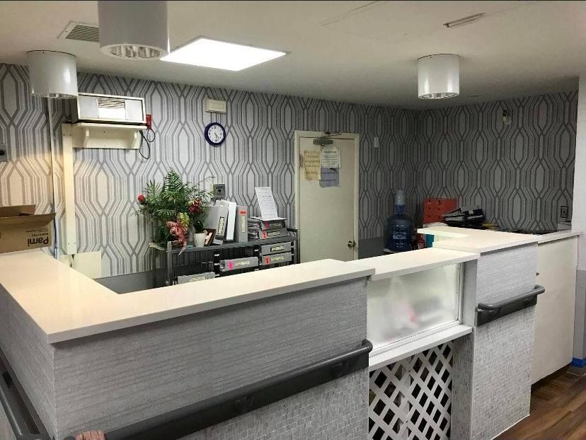 A front desk counter with gray patterned wallpaper in a brightly lit office or reception area.