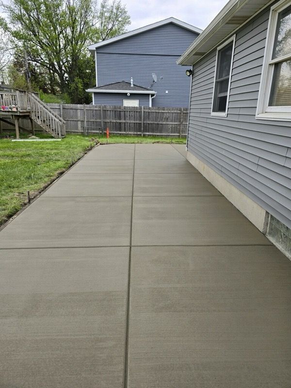 A concrete driveway leading to a house with a fence in the backyard