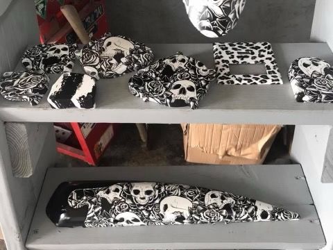 Various objects with a black and white skull and rose pattern displayed on gray shelves.