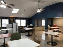 A large room with tables and chairs and a ceiling fan