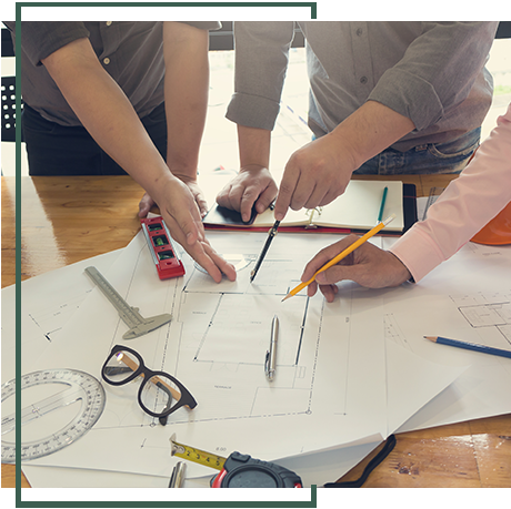 A group of people are sitting around a table looking at a blueprint. A group of people are sitting around a table looking at a blueprint.