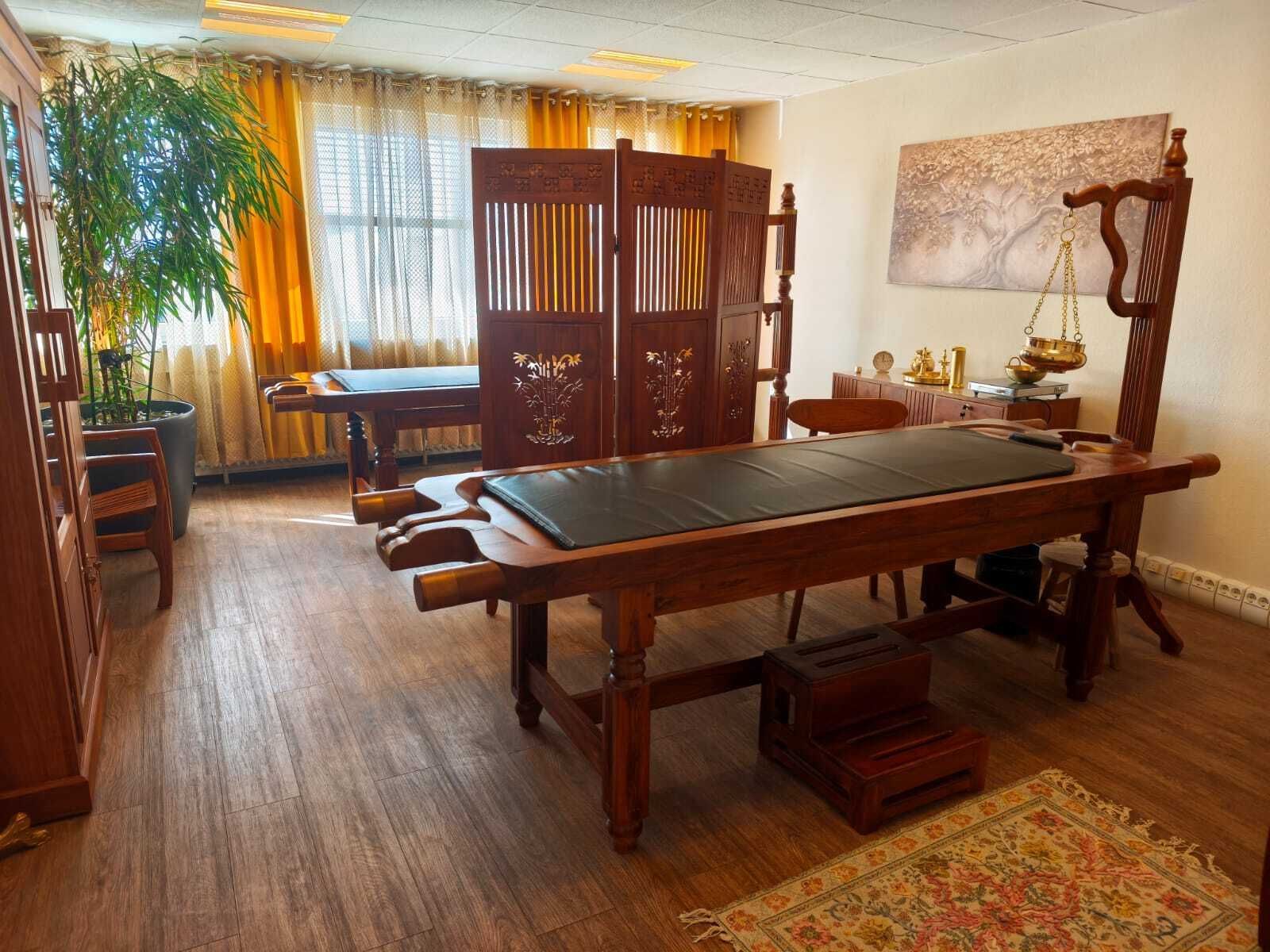 Behandlungsraum im Spa mit Massageliege, Raumteilern aus Holz, Pflanzen und warmem Licht