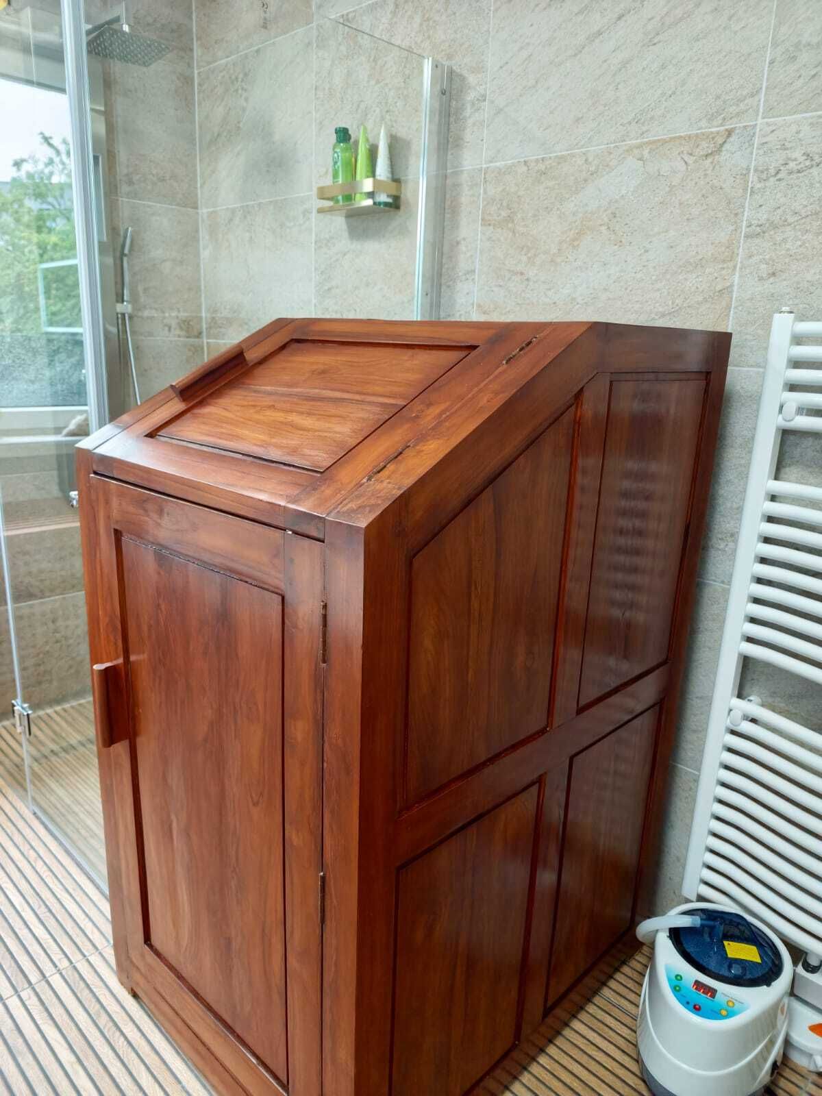 Wäschekorb-Schrank aus Holz in einem Badezimmer neben einer Dusche und einem Heizkörper.