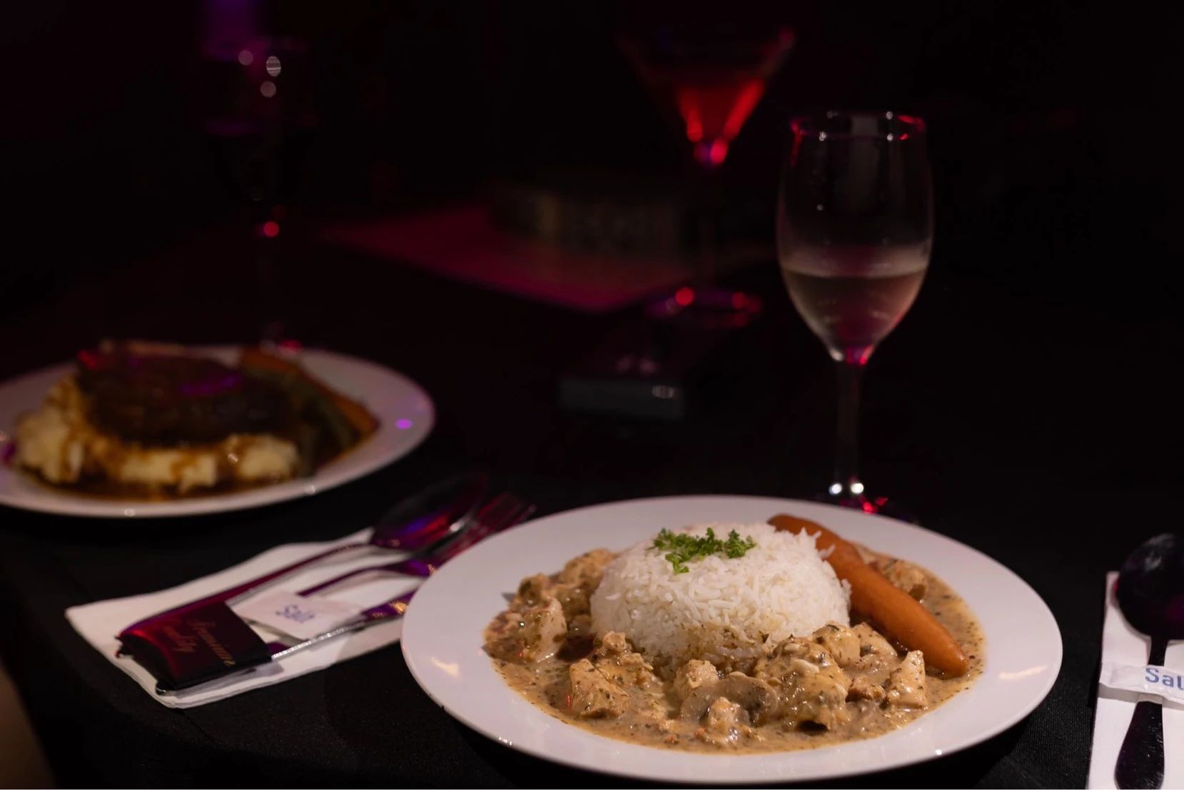 A Plate Of Food And A Glass Of Wine On A Table In A Restaurant — Lux Noir In  Mackay, QLD