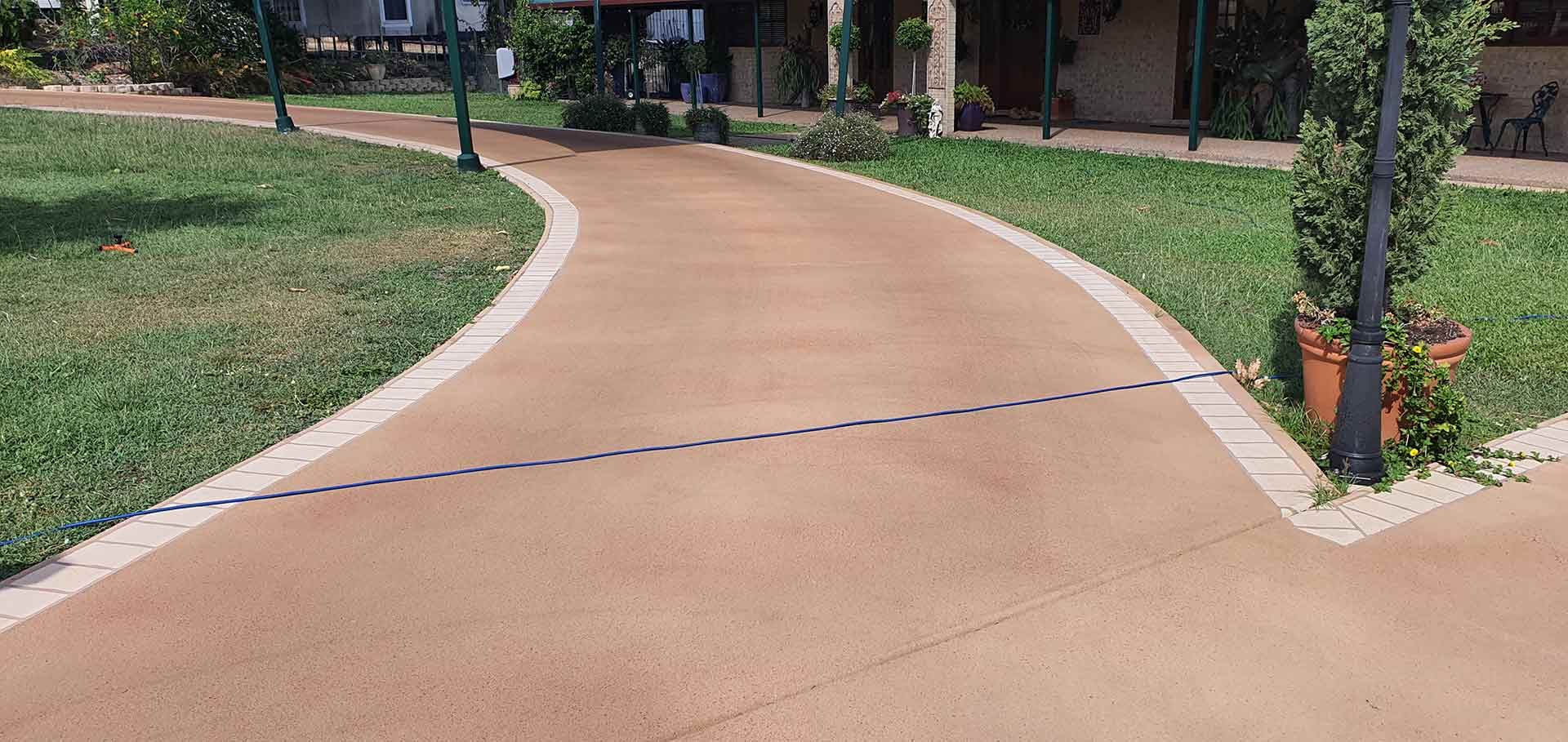 Curved Driveway Going Through A Lush Green Field — Diamond Concreting In Mount Low, QLD