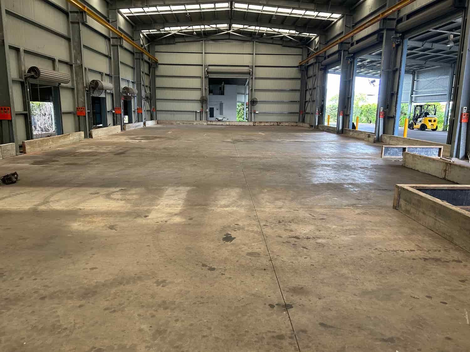 A Large Empty Warehouse With a Forklift in the Background — Diamond Concreting In Mount Low, QLD
