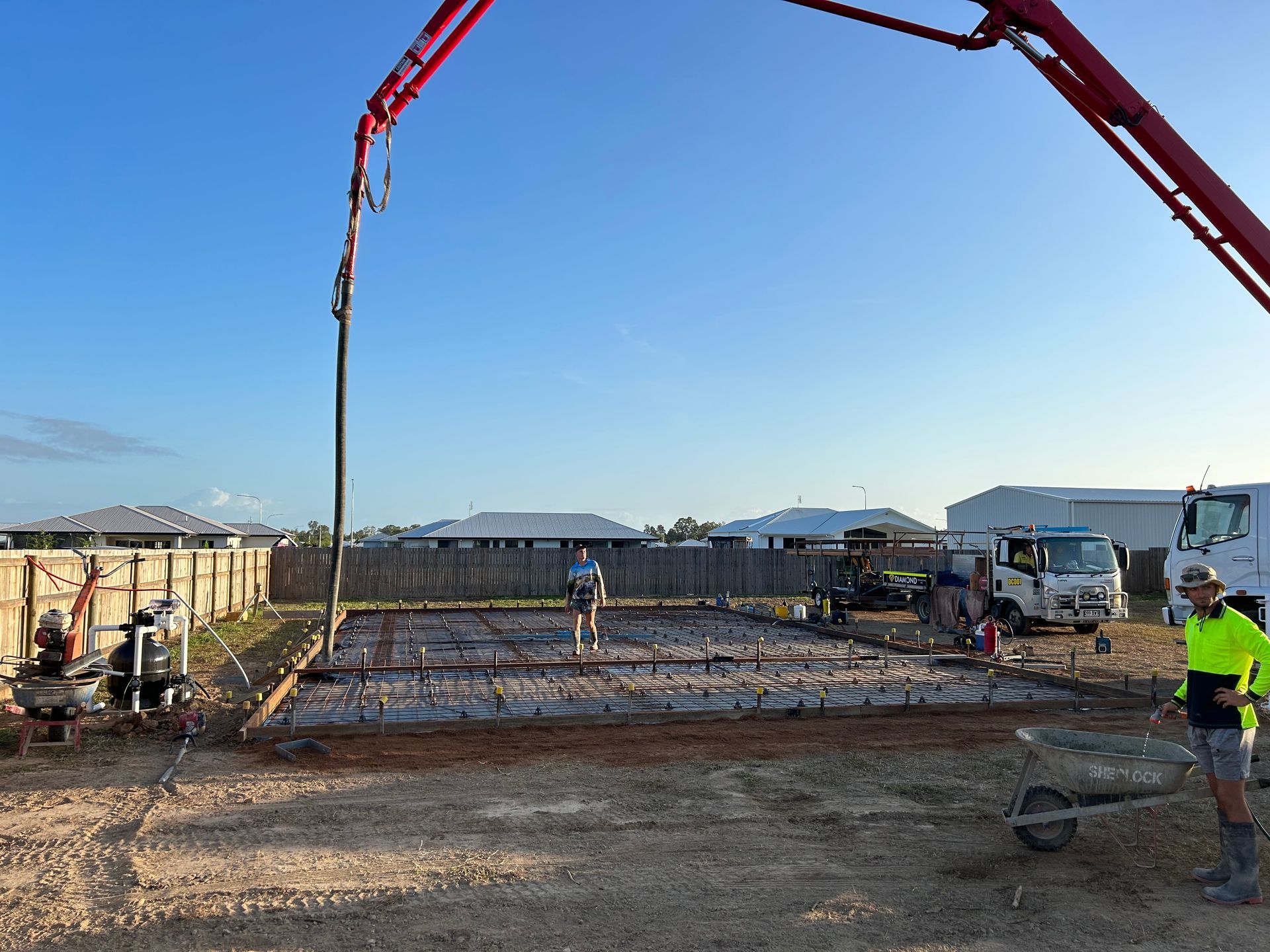 Two Men Working On A Stone Wall With A Bulldozer — Diamond Concreting In Mount Low, QLD