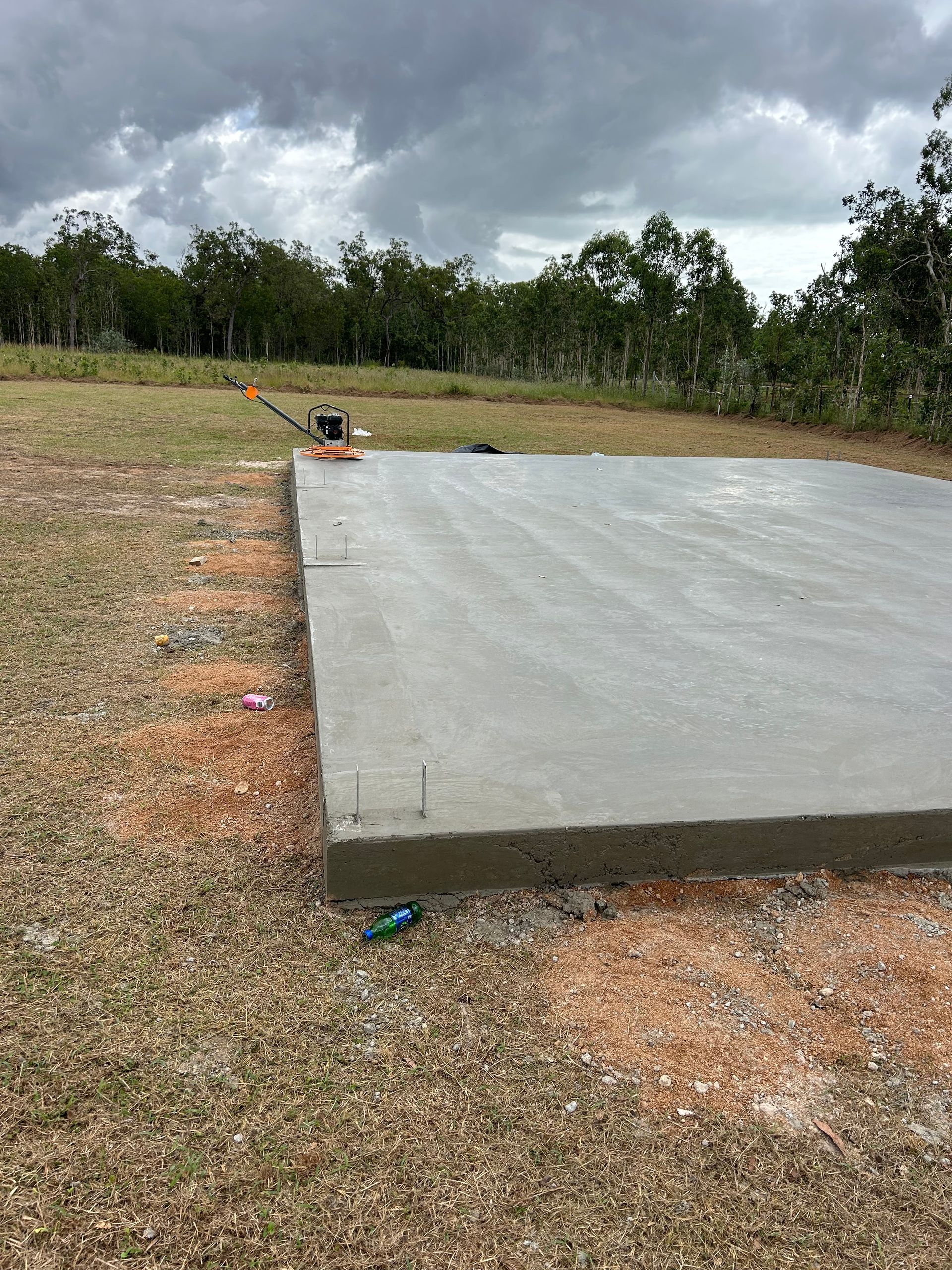 Concrete Floor Being Built In A Backyard Next To A Green Fence — Diamond Concreting In Mount Low, QLD