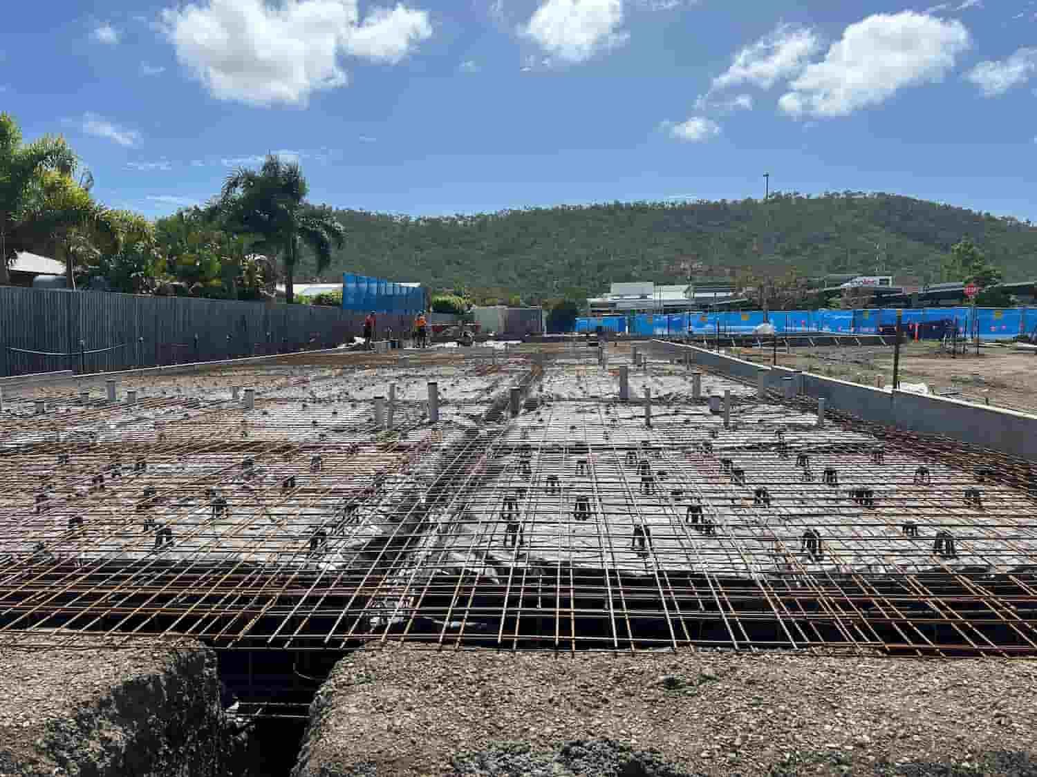 A Construction Site With a Fence and a Mountain in the Background — Diamond Concreting In Mount Low, QLD