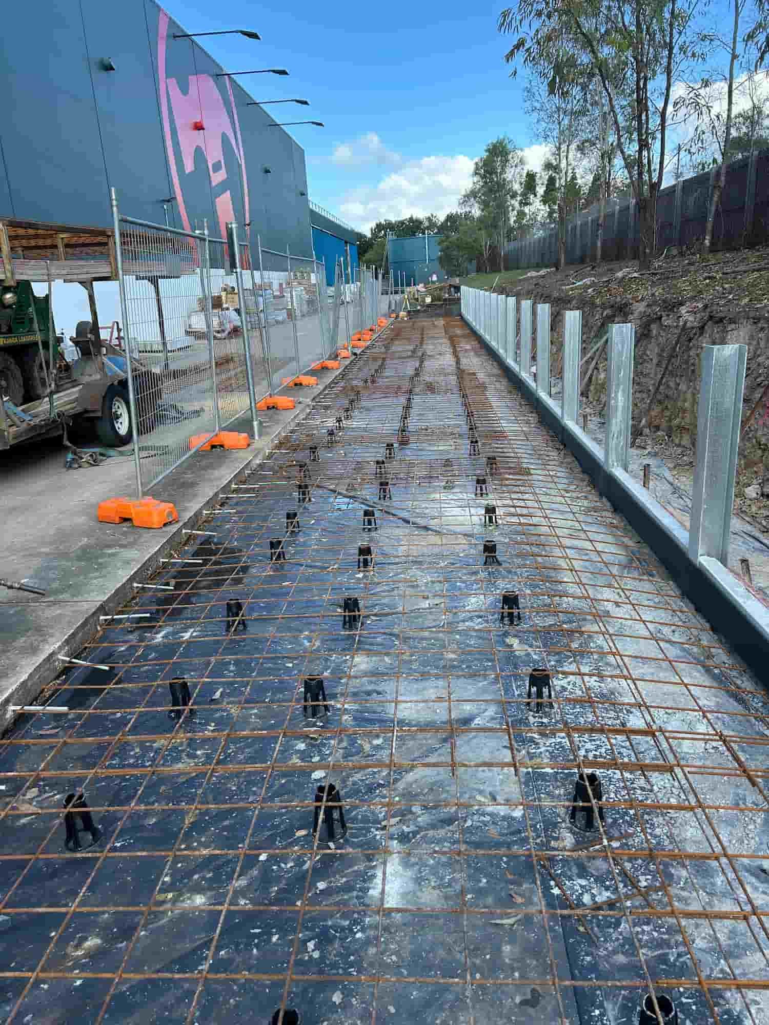 A Concrete Road is Being Built Next to a Building — Diamond Concreting In Mount Low, QLD