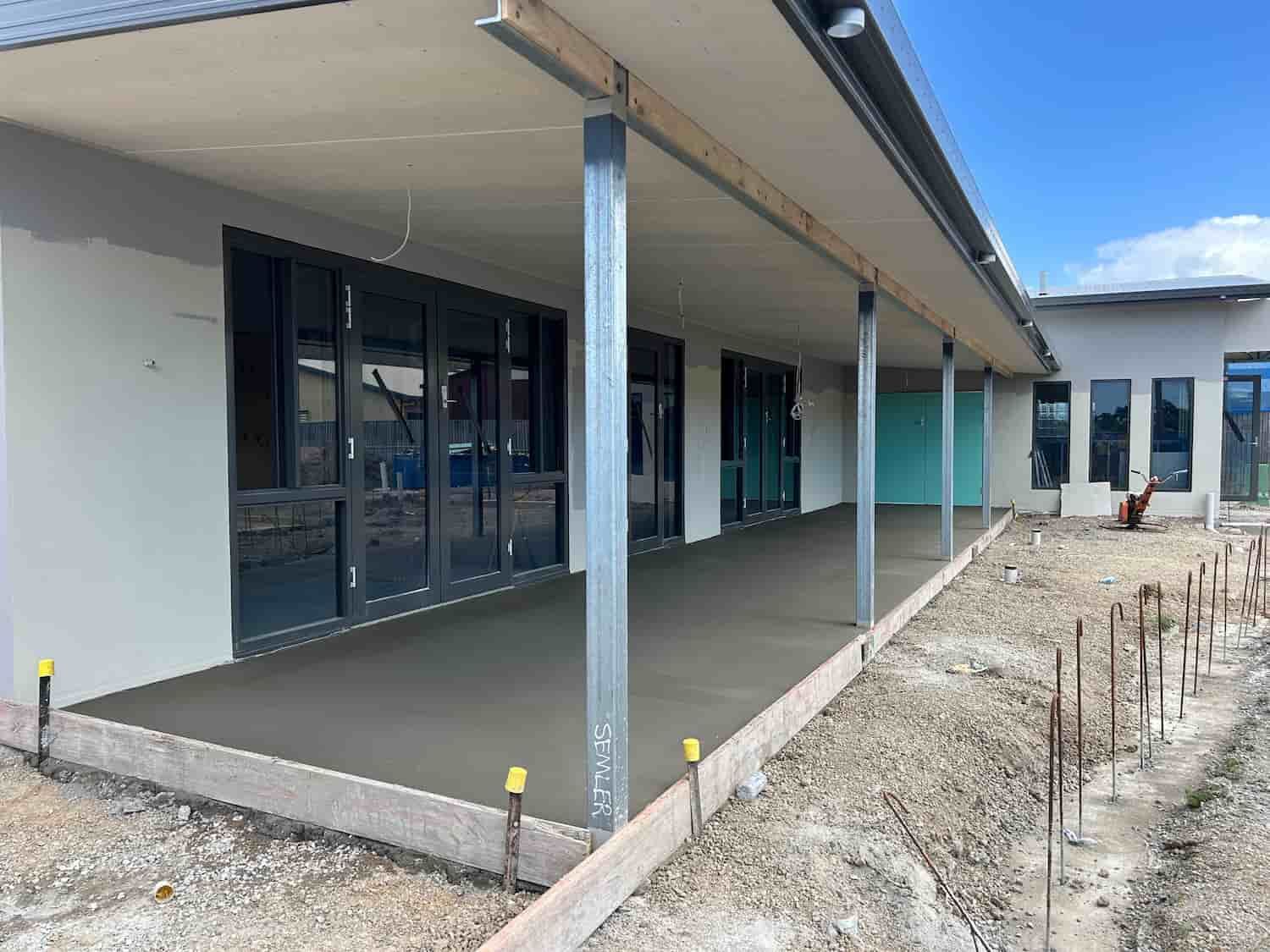 A Large Building Under Construction With a Concrete Walkway Leading to It — Diamond Concreting In Mount Low, QLD