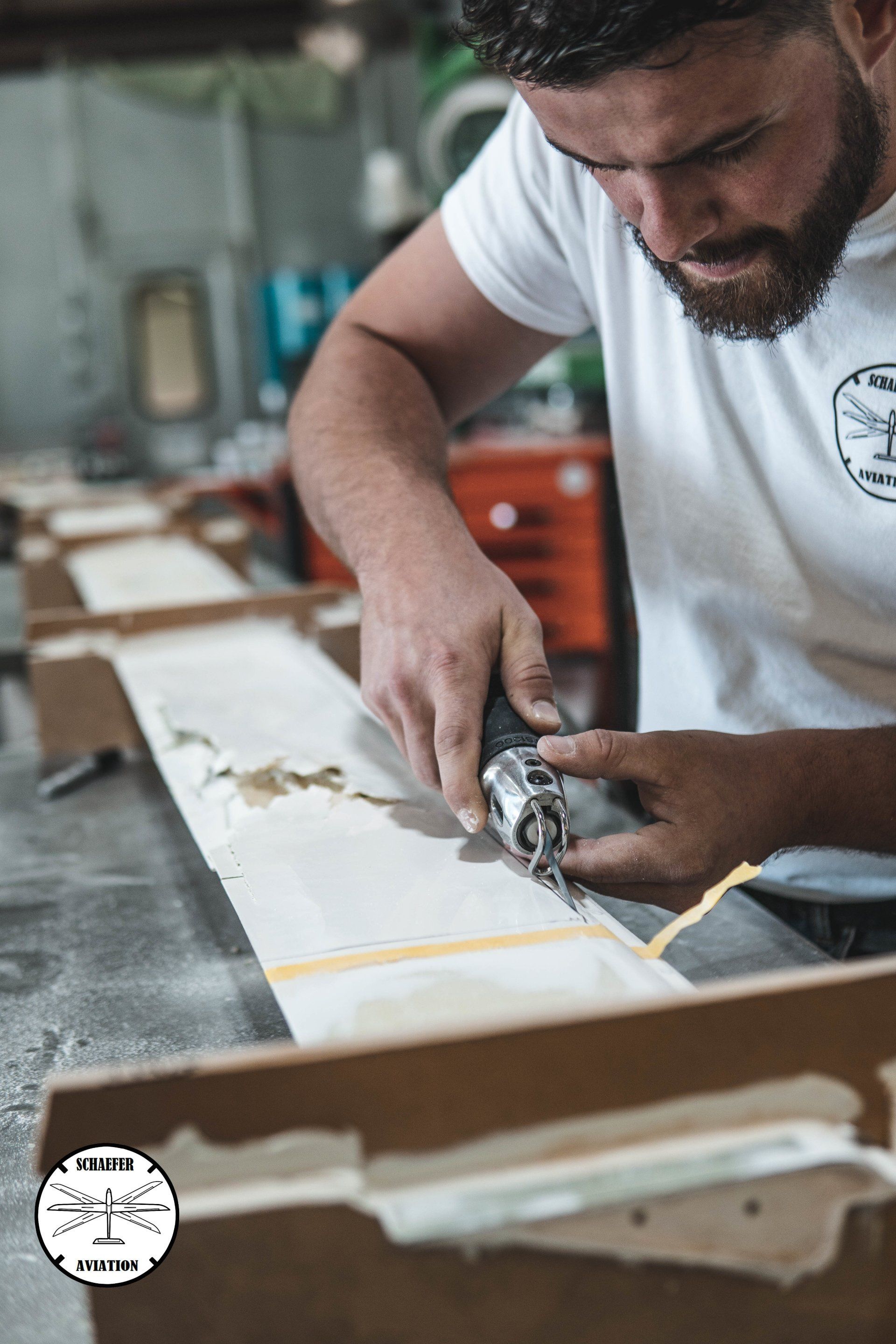 A man is using a drill to cut a piece of wood.