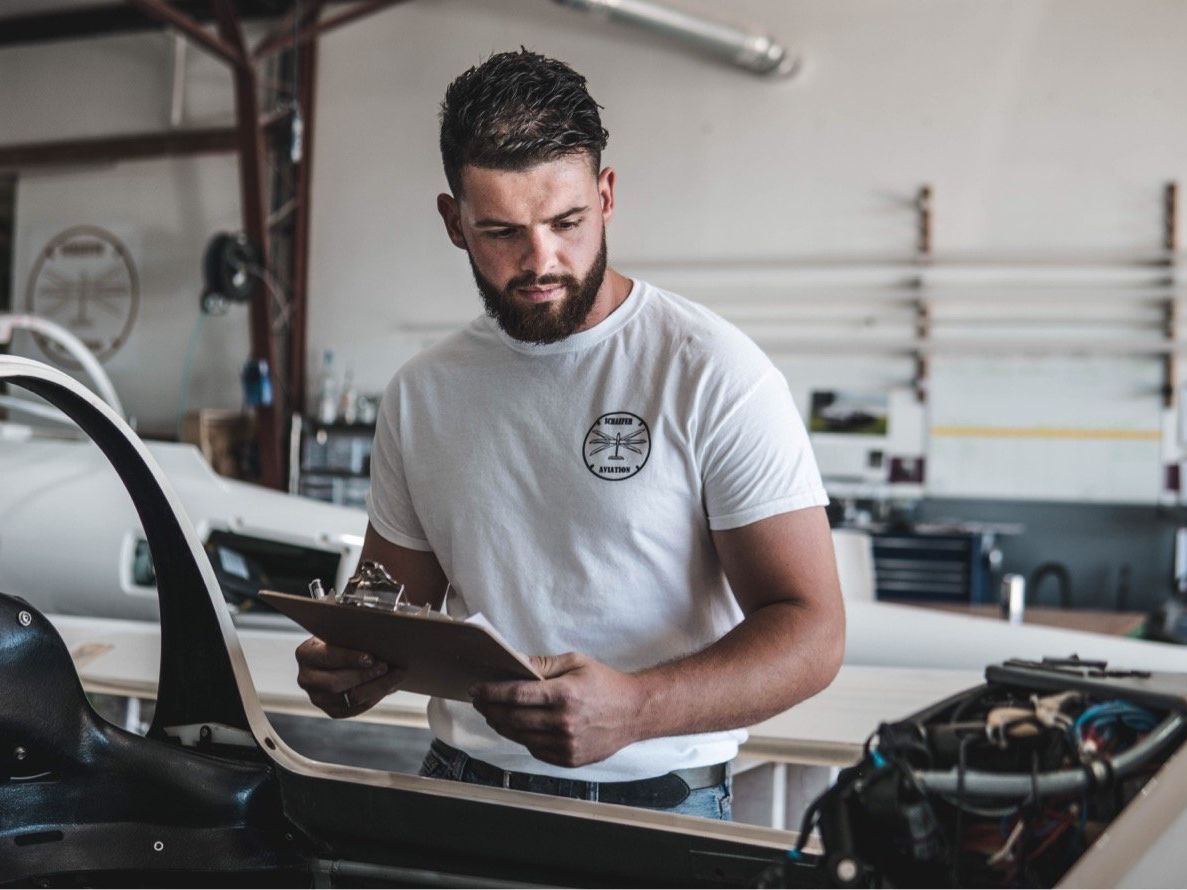 A man is looking at a clipboard in a garage.