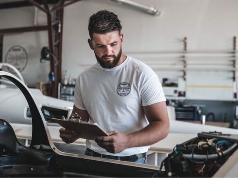 A man is looking at a clipboard in a garage.