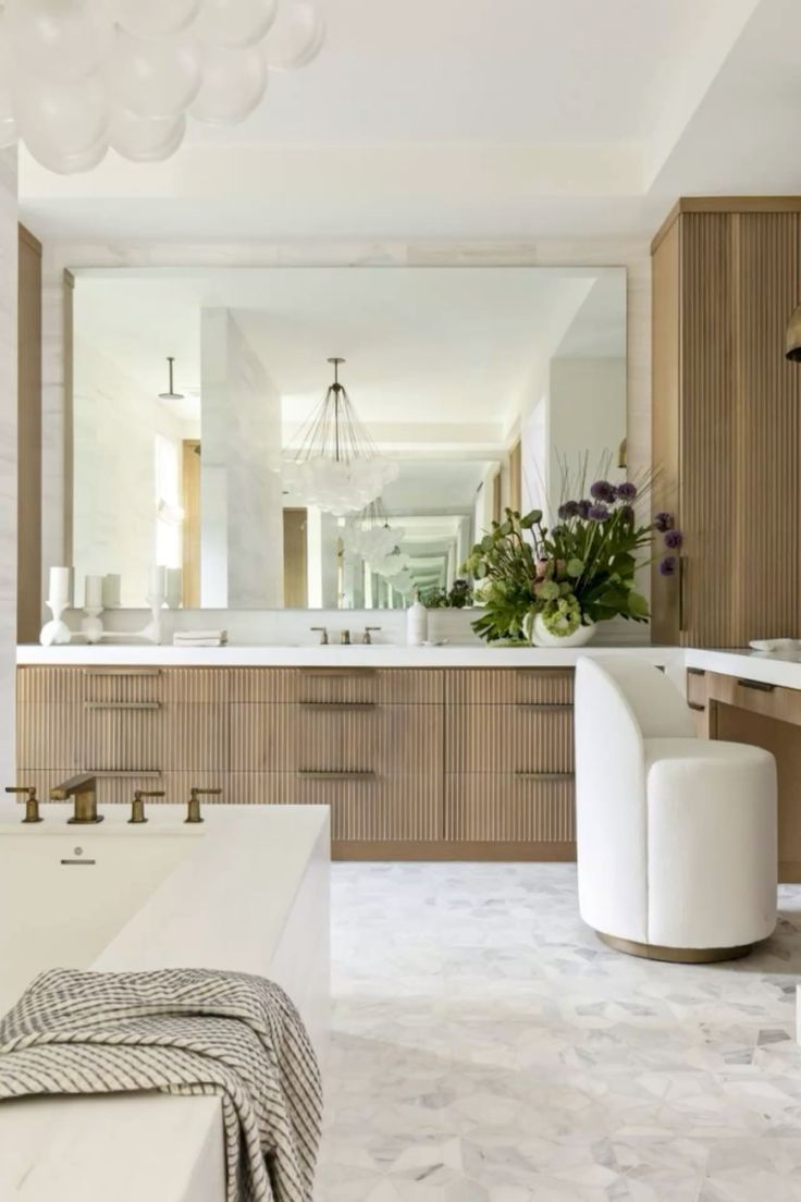 A bathroom with a tub , sink , mirror and chair.