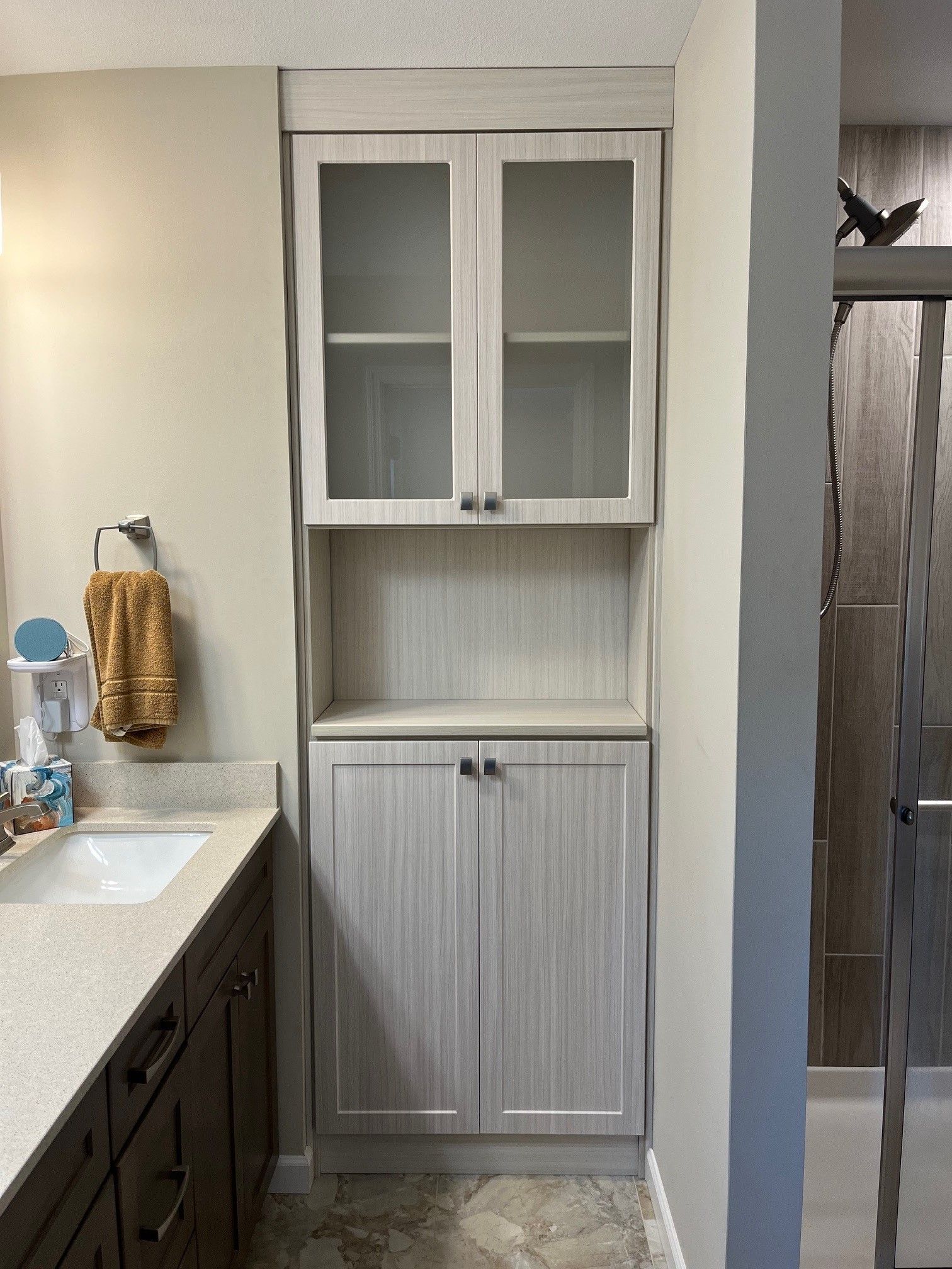 Small bathroom vanity with white cabinet storage and dark wood drawers, beside a sink and mirror.