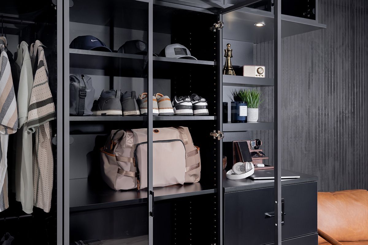 Open closet with shelves of clothes, shoes, and bags in a dark bedroom.