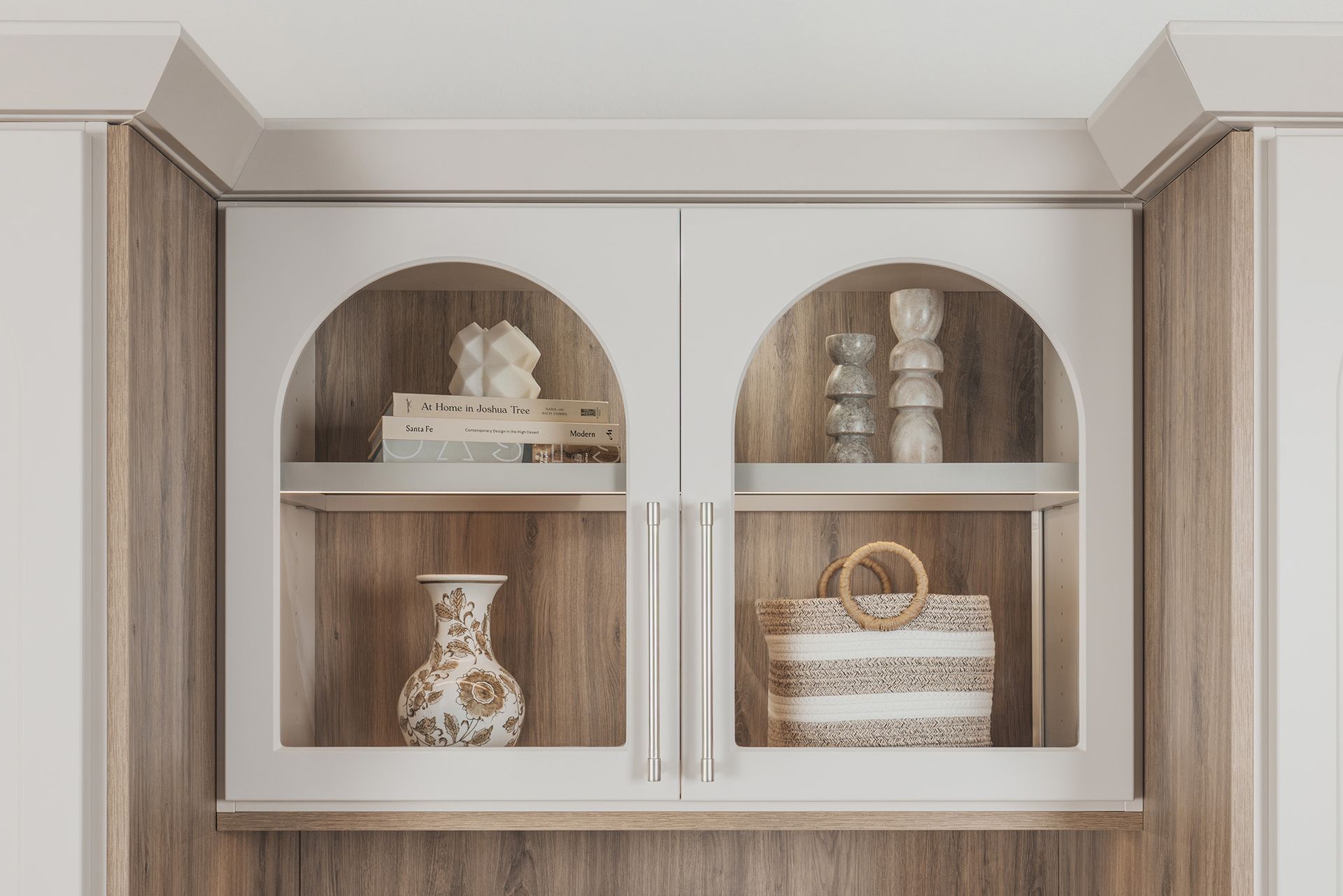 Built-in cabinet with arched glass doors displaying decorative vases and stacked bowls on wooden shelves