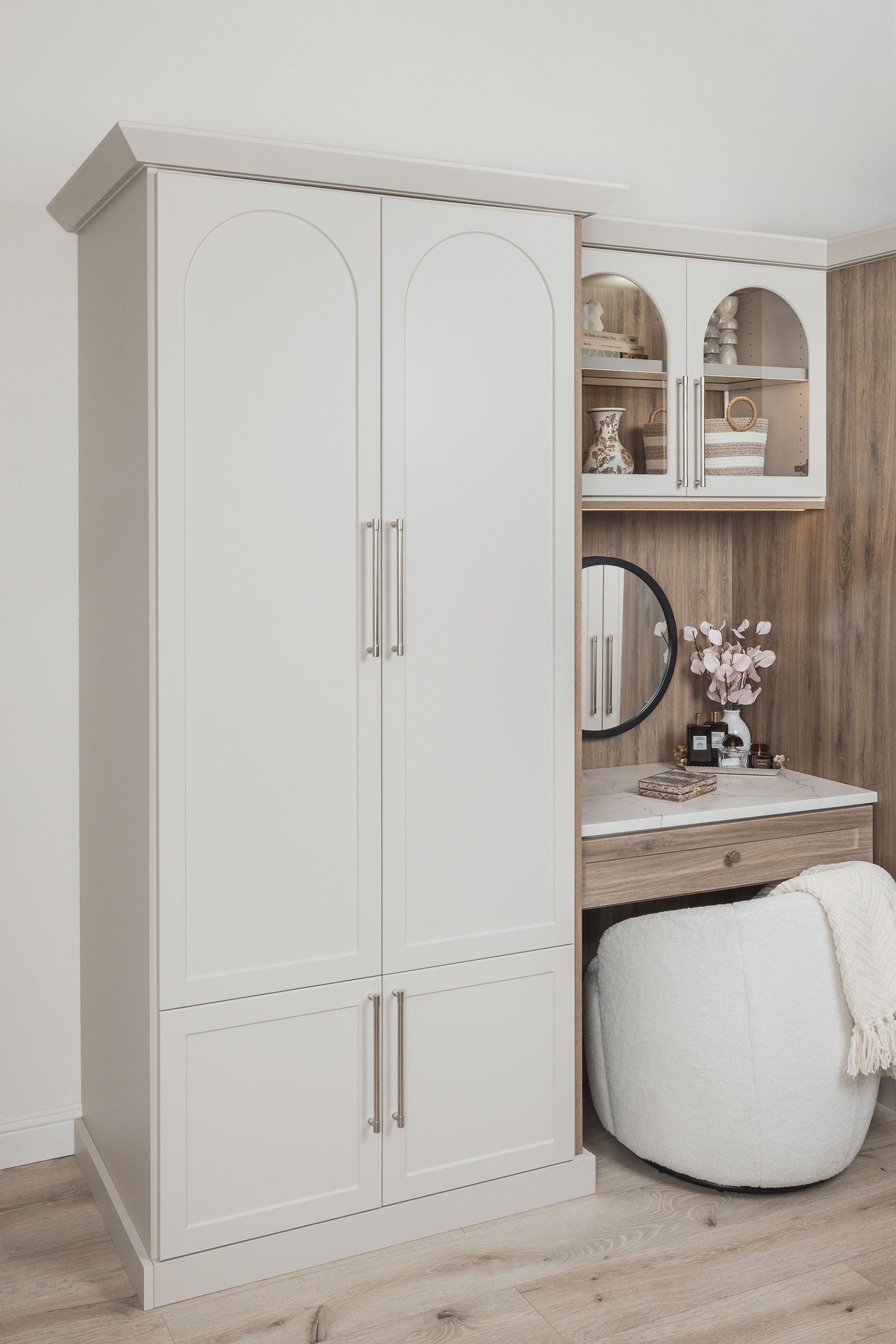 White wardrobe and vanity corner with mirror, shelves, beige wall paneling, and a white pouf stool