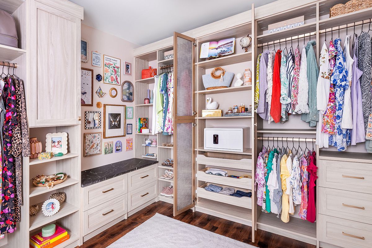 Walk-in closet with organized shelves, drawers, hanging clothes, and storage bins in a bright neutral room