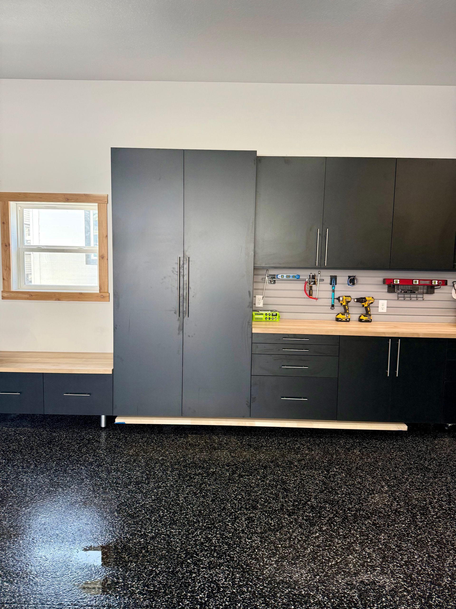 Garage or workshop interior with dark cabinets, a counter, and a small window on the left.