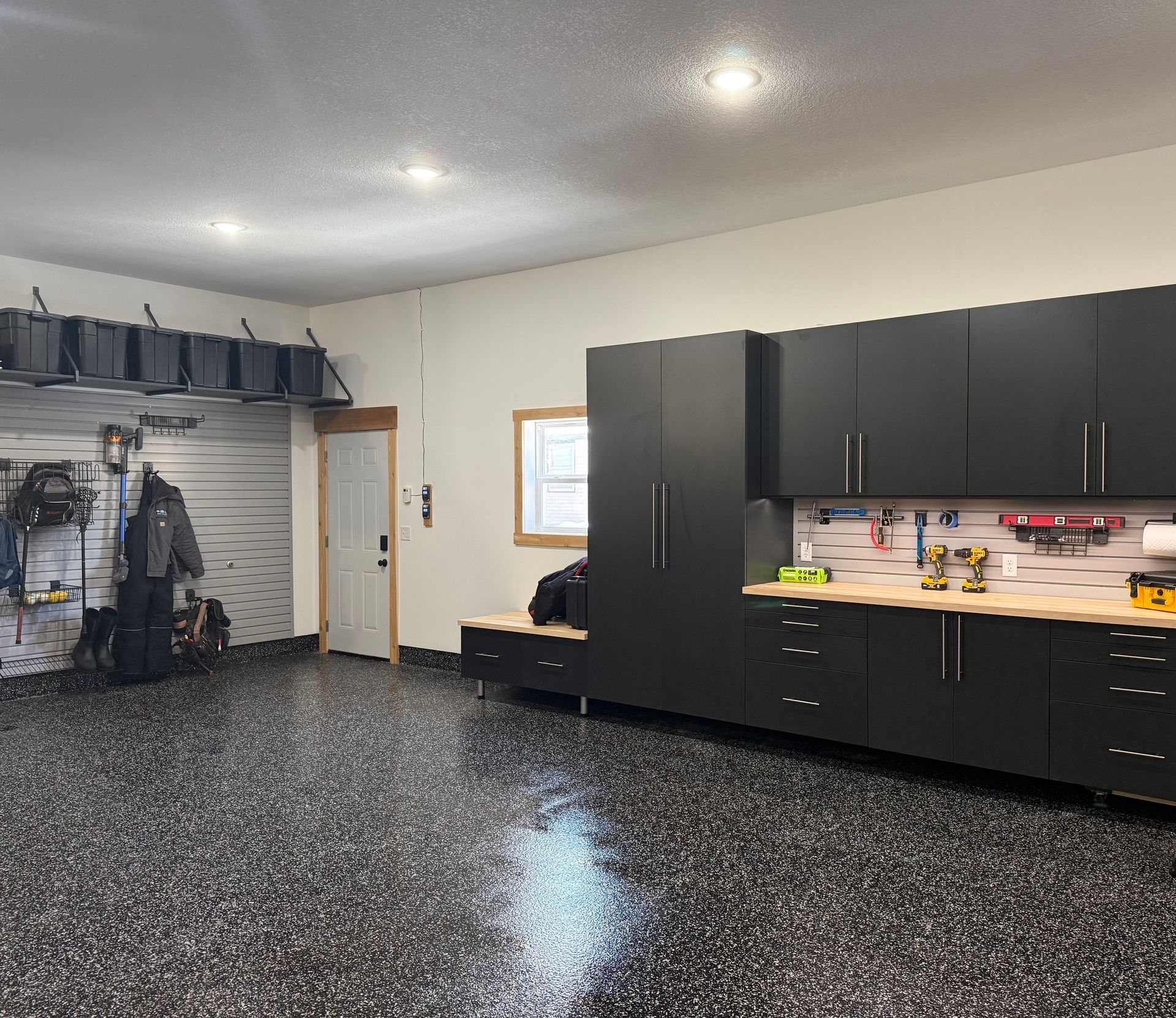 Garage workshop with black cabinets, workbench, and speckled epoxy floor.
