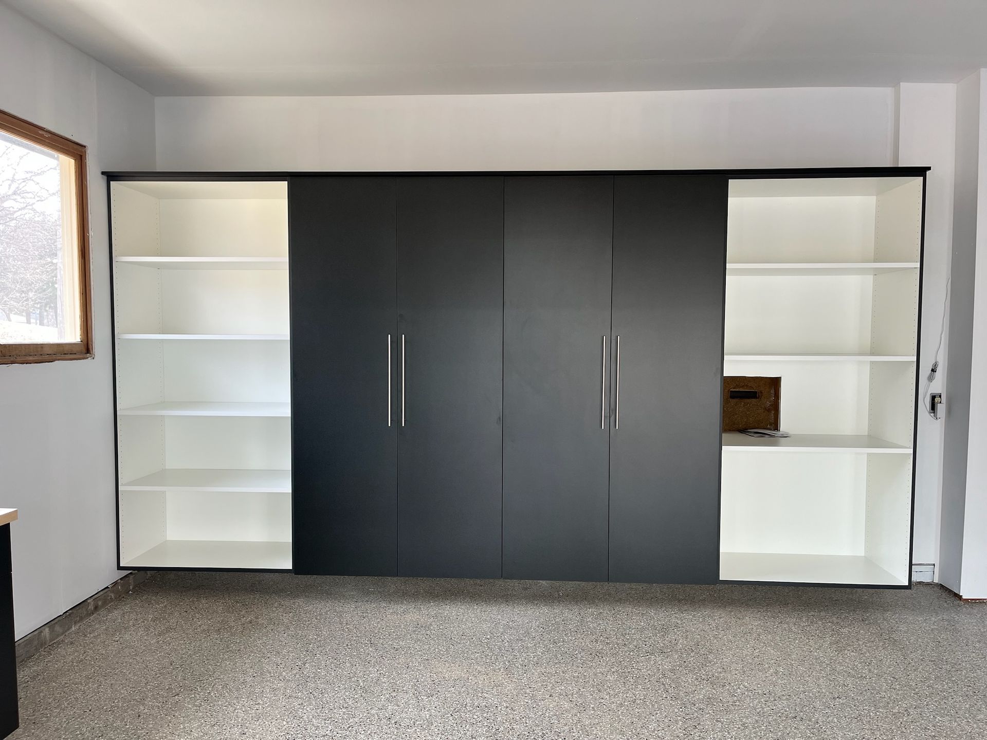 Built-in wall cabinets with dark center doors and white shelving in a carpeted room.