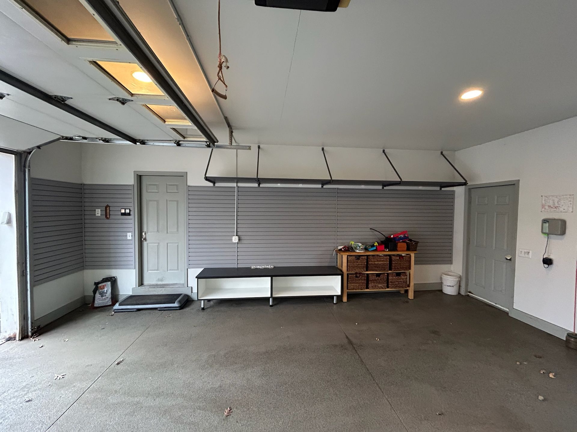 Empty garage with white walls, gray floor, and storage cabinets along the back wall