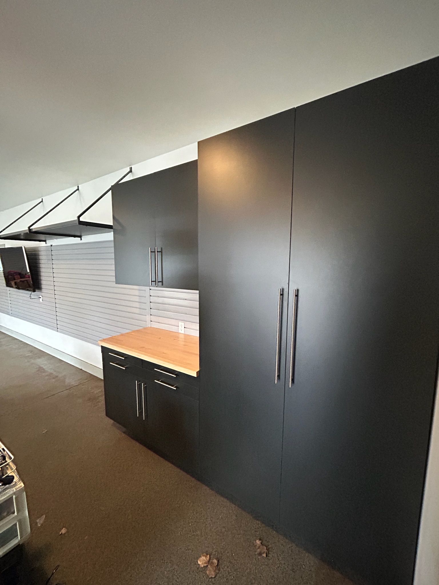 Modern kitchen with dark cabinets, white backsplash, and an orange countertop beneath a slanted ceiling